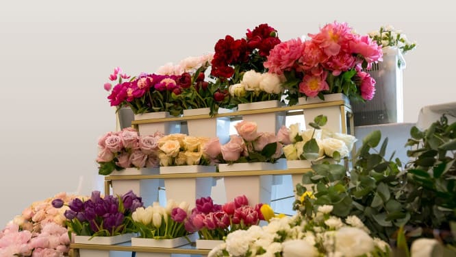Tiered display of assorted bouquets in white boxes with pink, red, white, and purple flowers