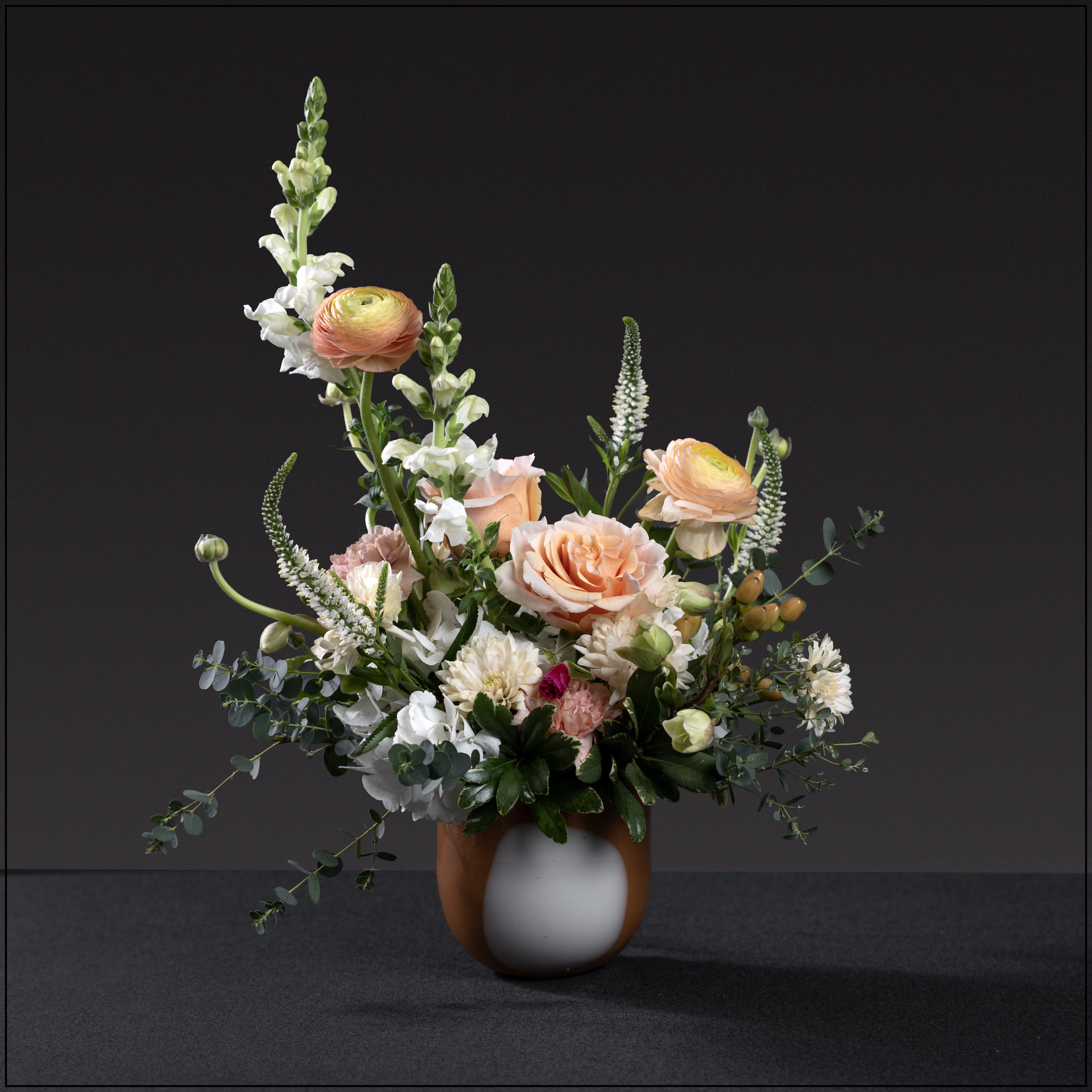Peaches - Gorgeous art glass vase filled with lush garden blooms. Roses, hydrangea, dianthus, snap dragons, hypericum, ranunculus, Helleborus, and veronica. Approximately 15" wide and 17" tall.