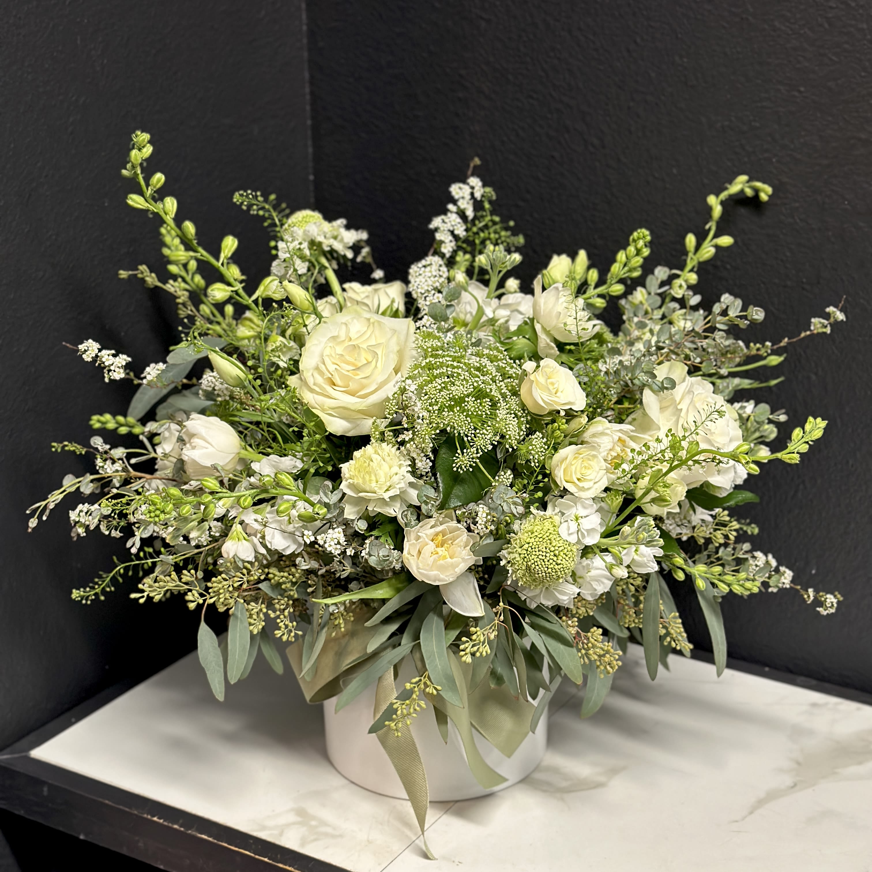 Moonlit Meadow  - A loose and airy garden mix in creamy white blossoms. Delivered in a white ceramic vase. Overall design is approximately 15"H x 22"W x 15"D.  While the varieties may vary the overall look will be of similar style &amp; quality. 