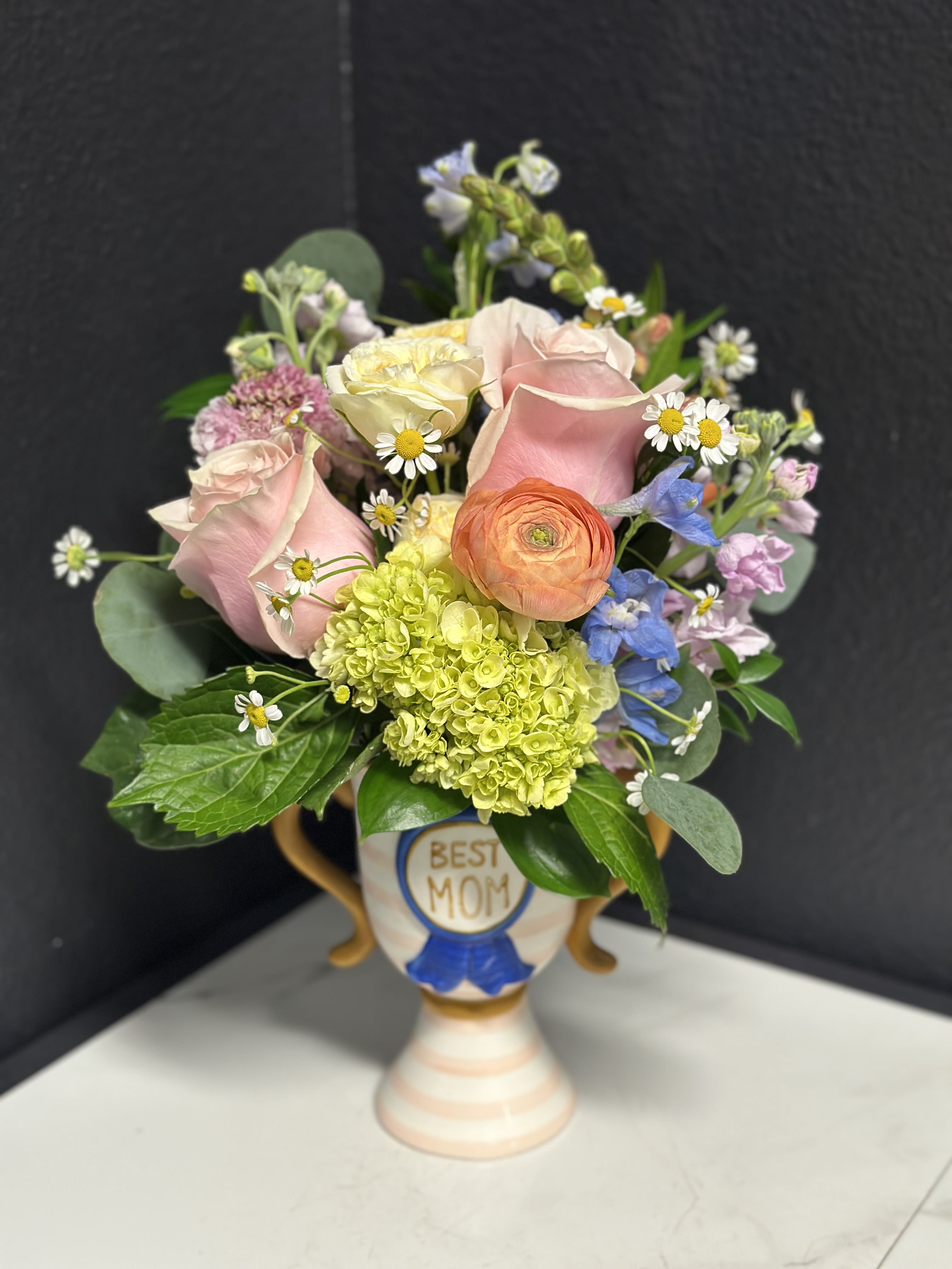 Trophy Mom - Let Mom know she's the absolute BEST! A pretty mix of seasonal pastel blooms arranged in our ceramic Trophy Mom vase.  Overall design is approximately 12" tall.  