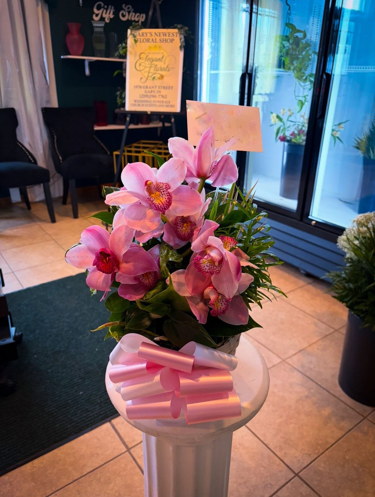 Orchid Whisper - A graceful and sophisticated arrangement featuring vibrant pink orchids with speckled centers, complemented by tropical greenery and finished with a soft pink bow. This design offers a luxurious, contemporary feel—ideal for birthdays, thank-you gifts, or upscale occasions.  