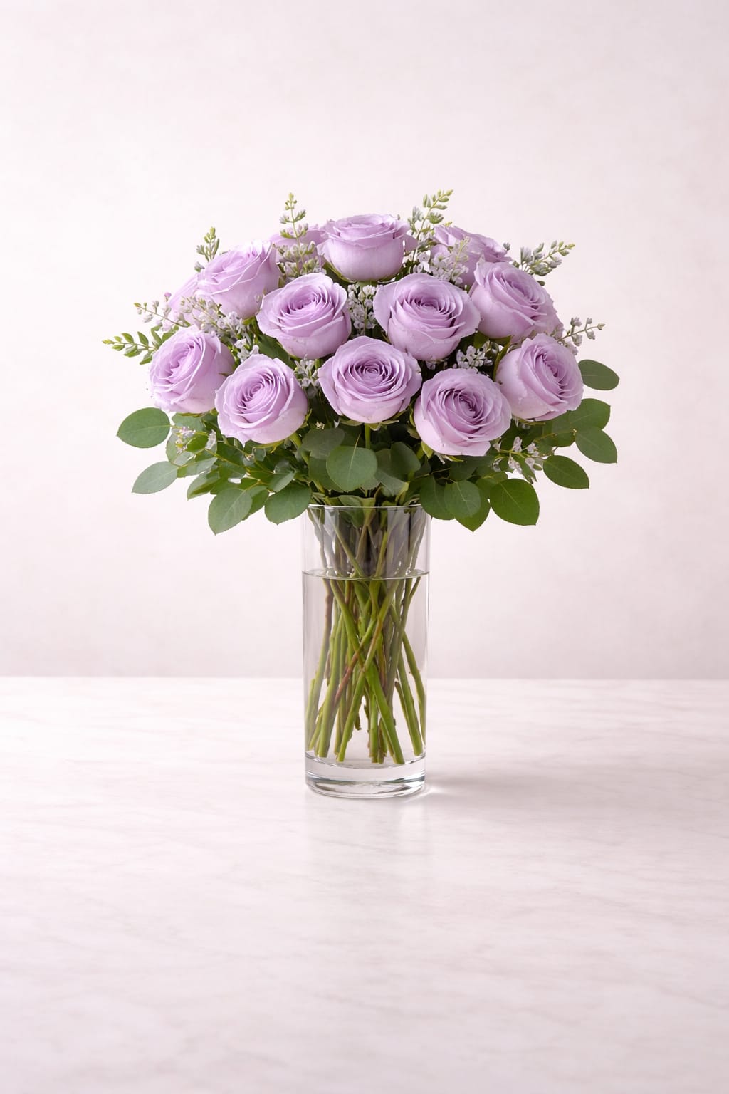 Tall glass vase with a dozen light lavender roses arranged in a rounded bouquet
