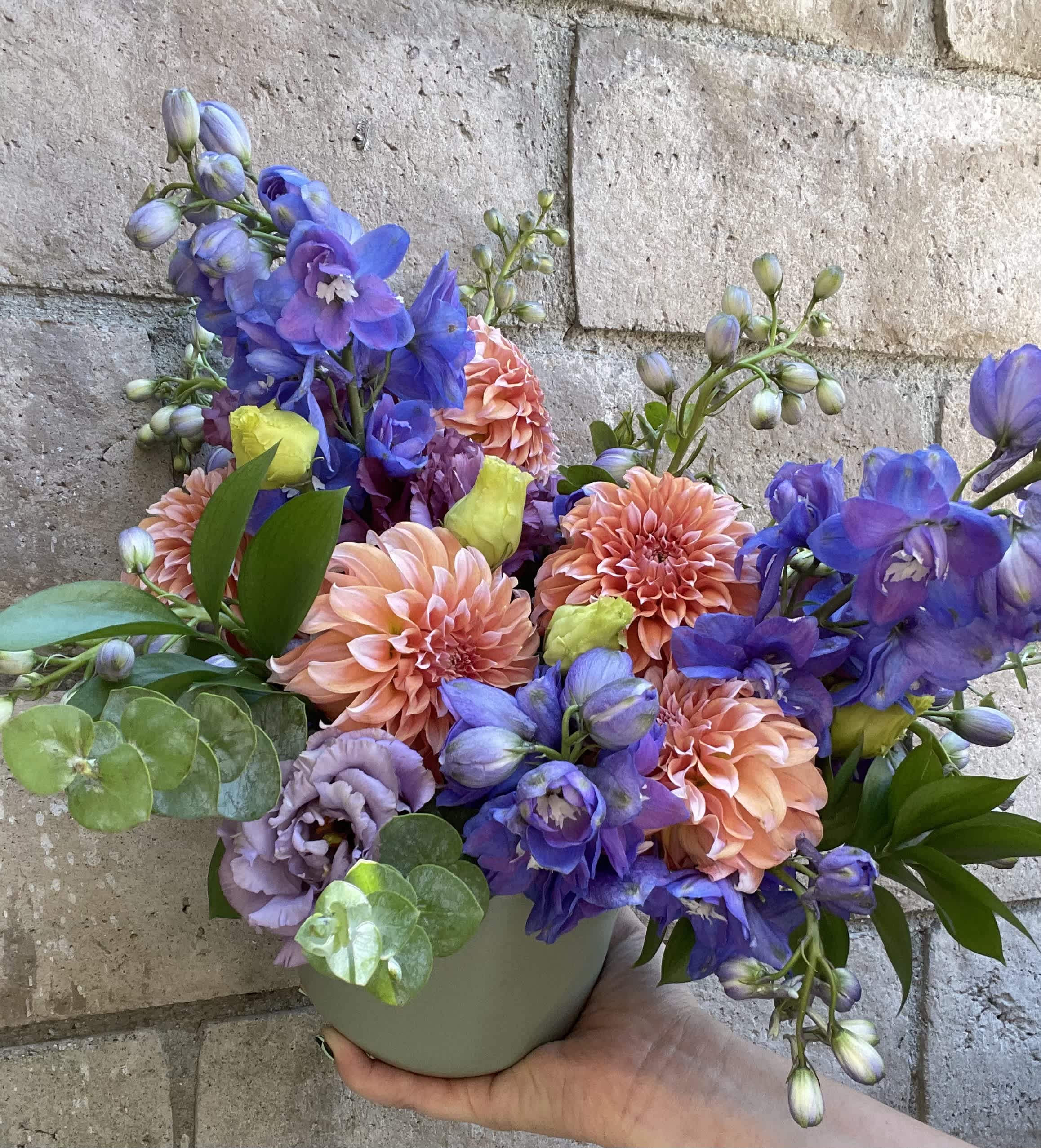 Colorful bouquet in a small gray vase with peach and purple flowers