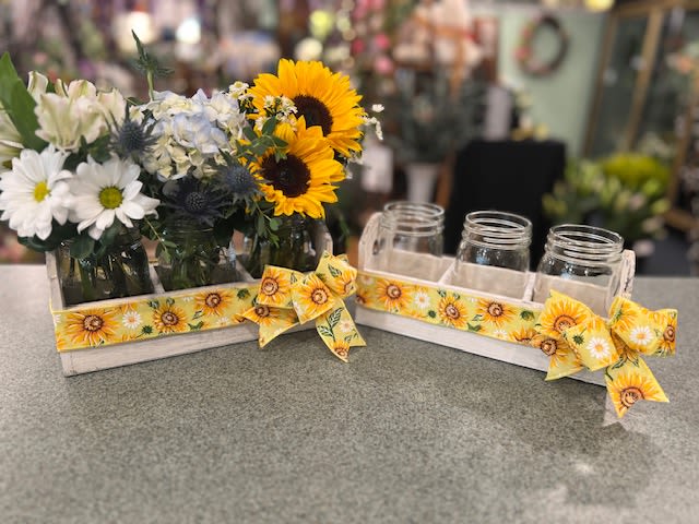 Sunflower and daisy arrangements in mason jars on a tray with sunflower ribbon
