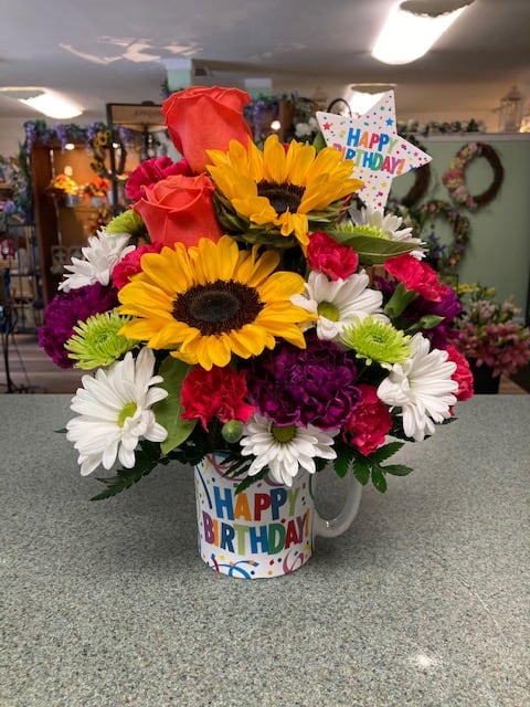 Birthday bouquet with sunflowers, roses, daisies, and carnations in a mug