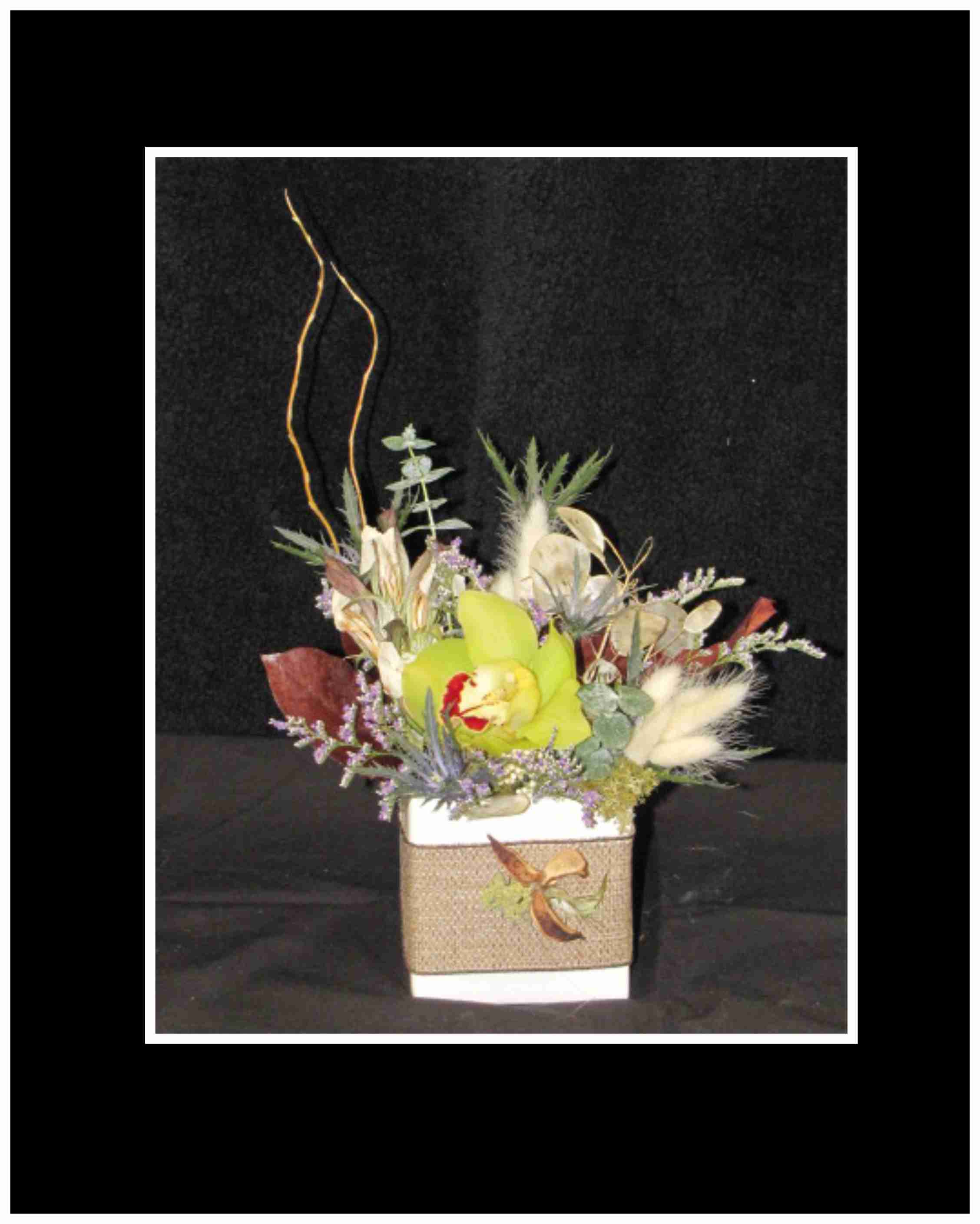 Mixed floral arrangement in a square white container with tall branches
