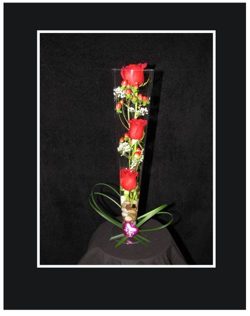 Tall glass vase with red roses and small white flowers