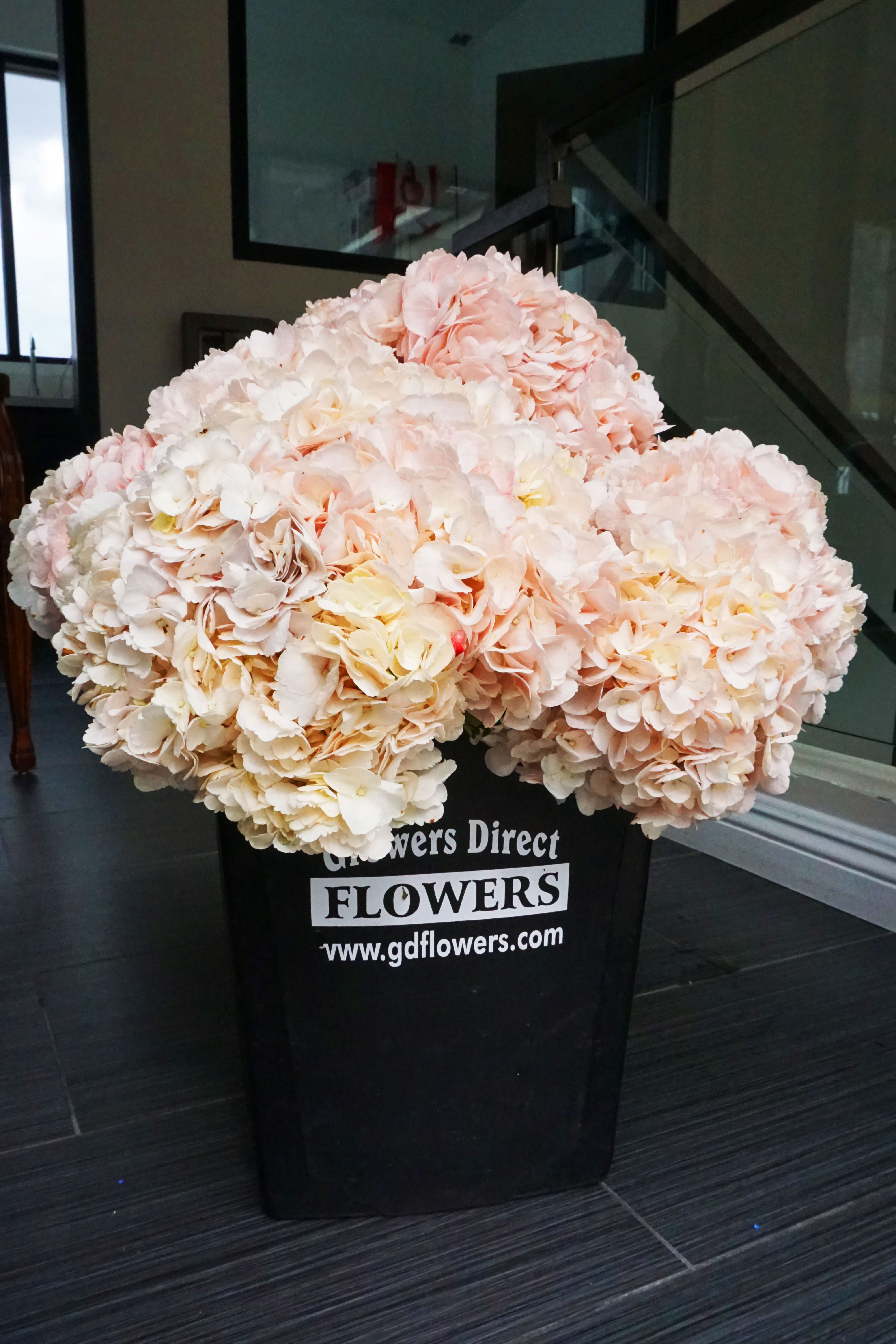Large bundle of blush and cream flowers in a black florist bucket