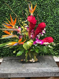 Tropical flower arrangement with bird of paradise and red blooms in a vase