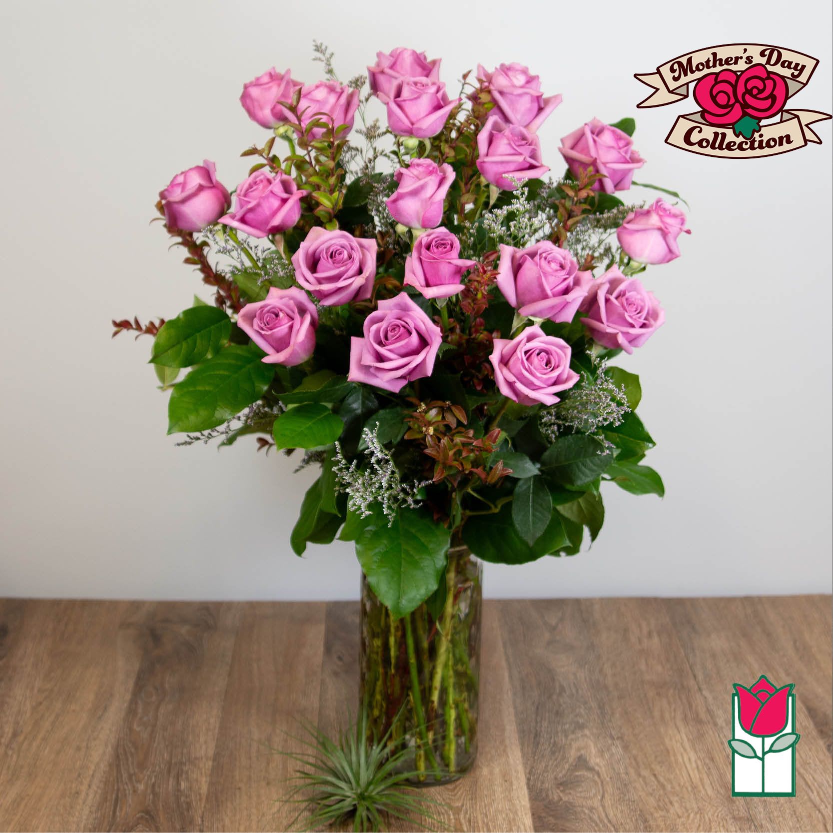 Pink roses arranged in a tall glass vase with greenery.