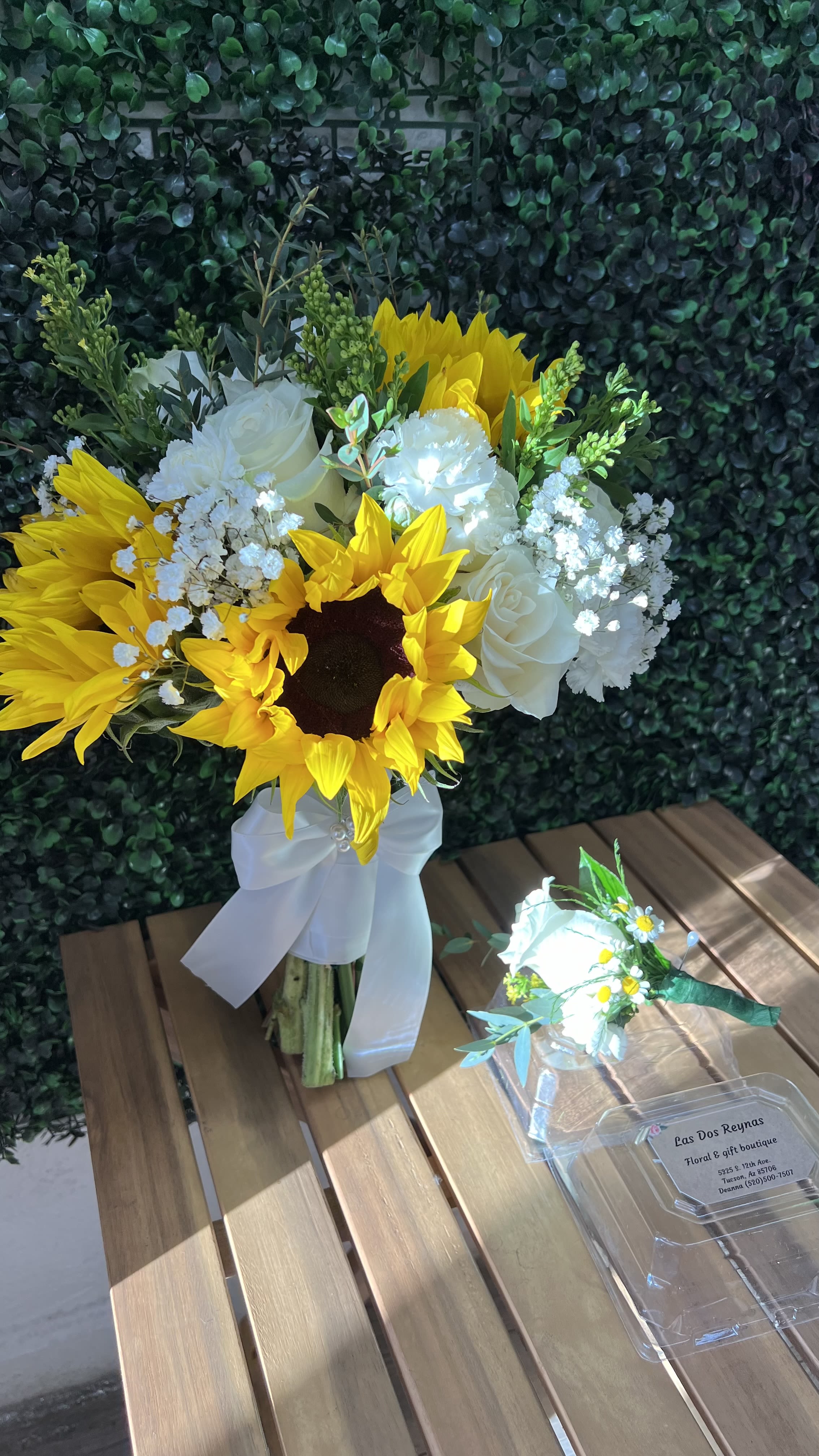 Golden Garden Charm  - A bright and elegant arrangement featuring vibrant sunflowers, soft white roses and delicate Filler flower finished in a white satin ribbon ( please note price does alternate a pond change in blooms)