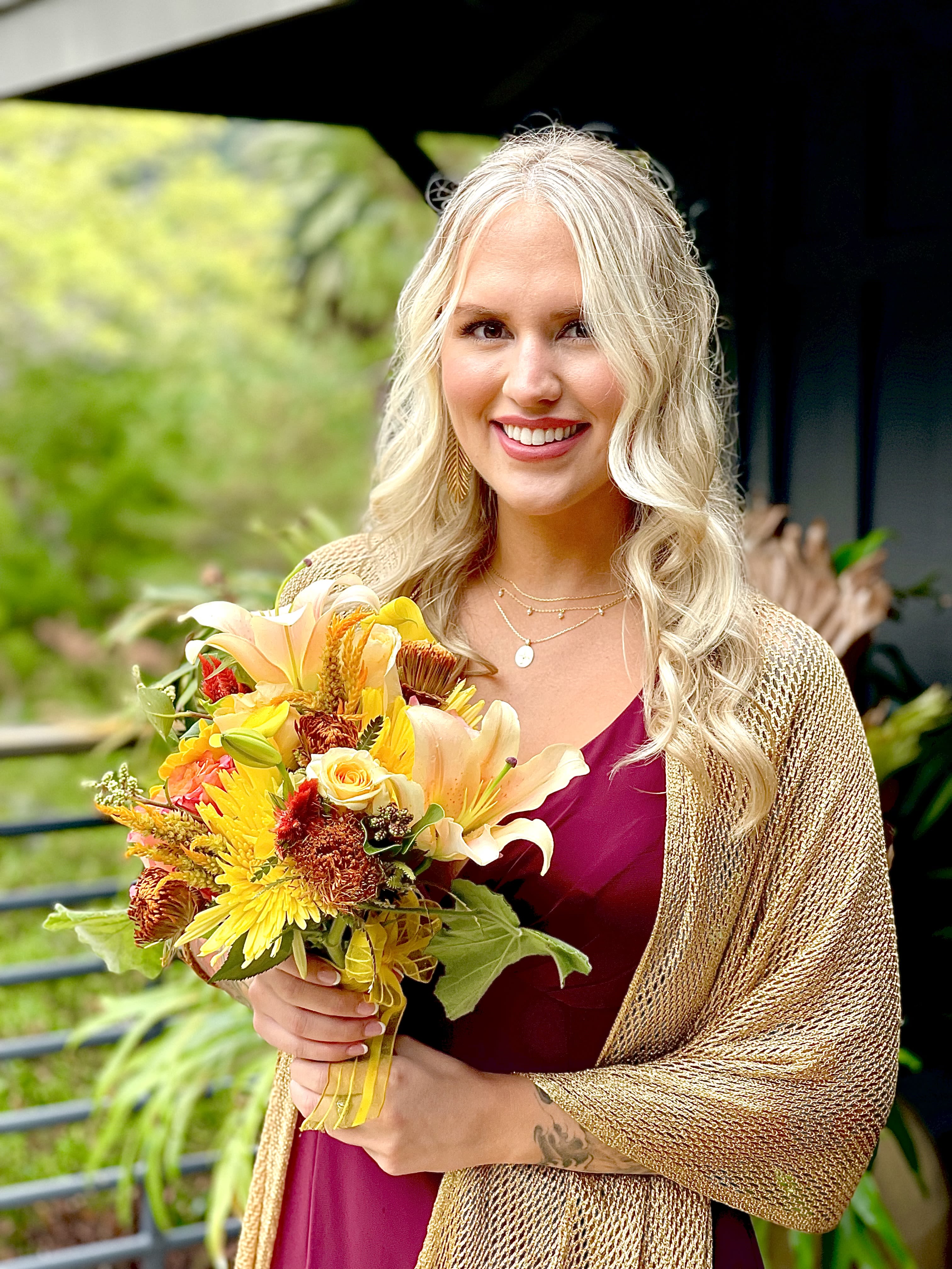 Woman holding a bouquet of yellow, orange, and white flowers
