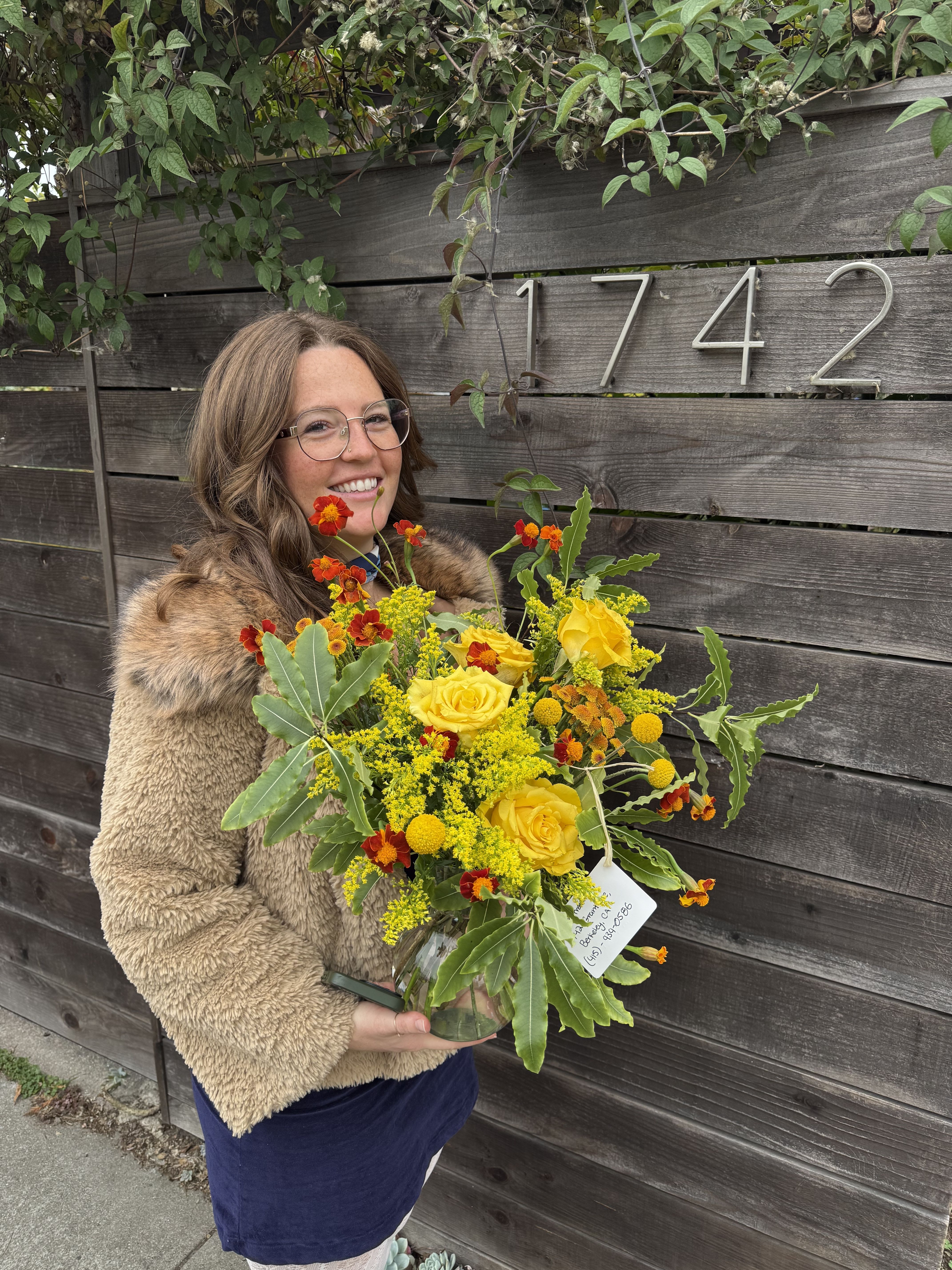 Woman holding a yellow and orange bouquet in a glass vase