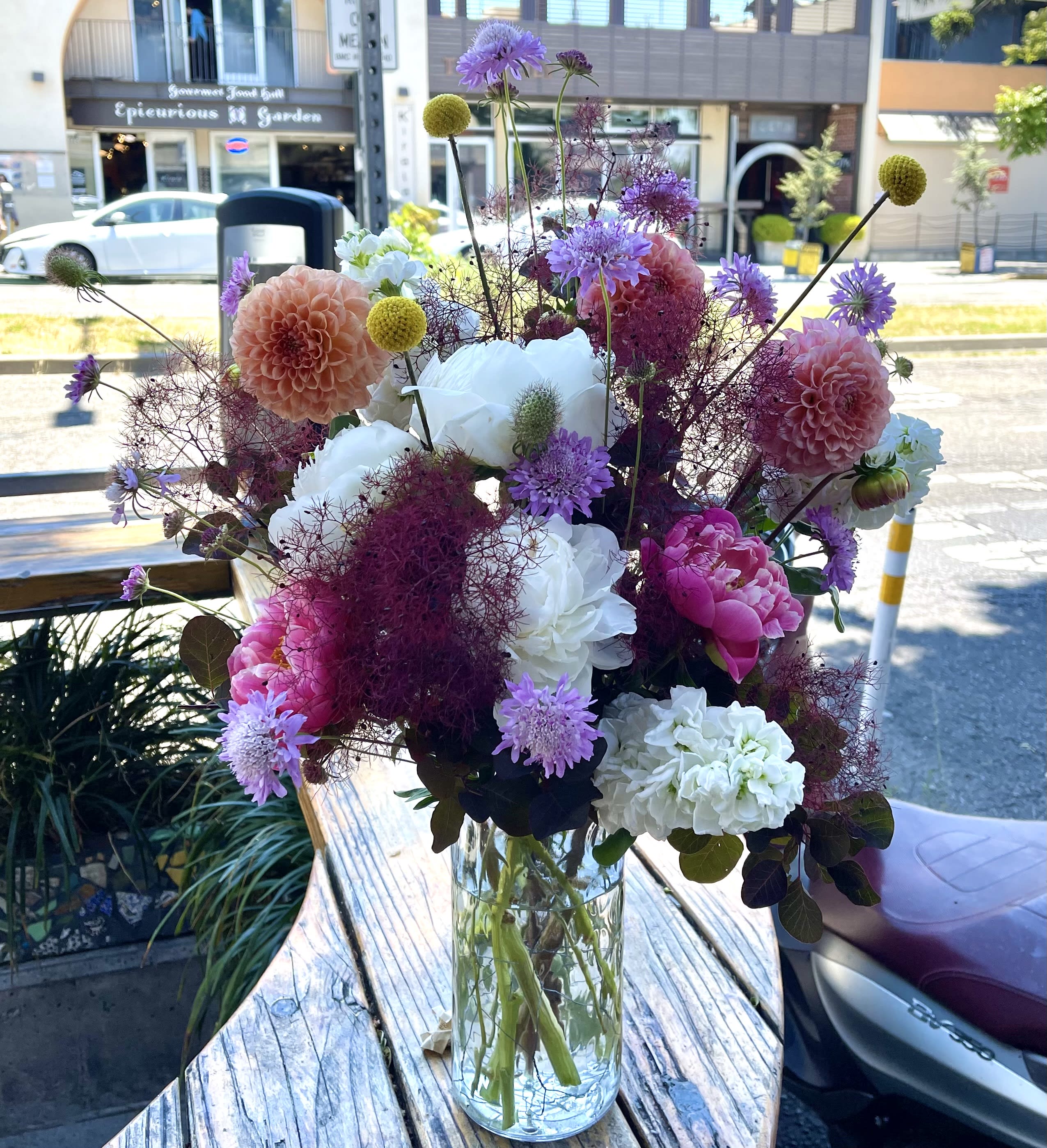 Mixed bouquet of pink, white, and purple flowers in a clear glass vase