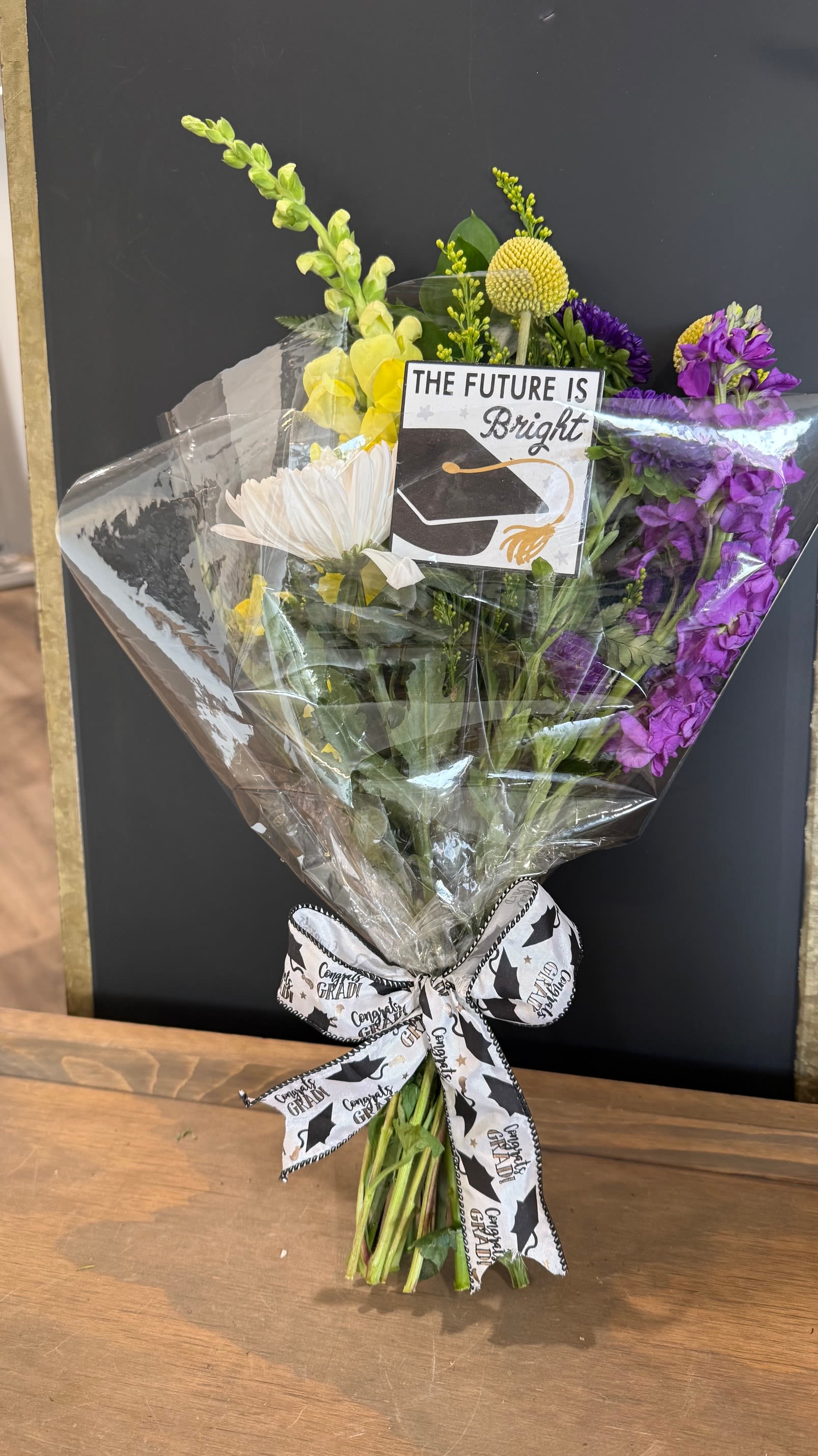 Rad Grad Flower Wrap - Show your love for your favorite grad with school-color themed blooms, tied with graduation themed ribbon and accented with a graduation themed pick