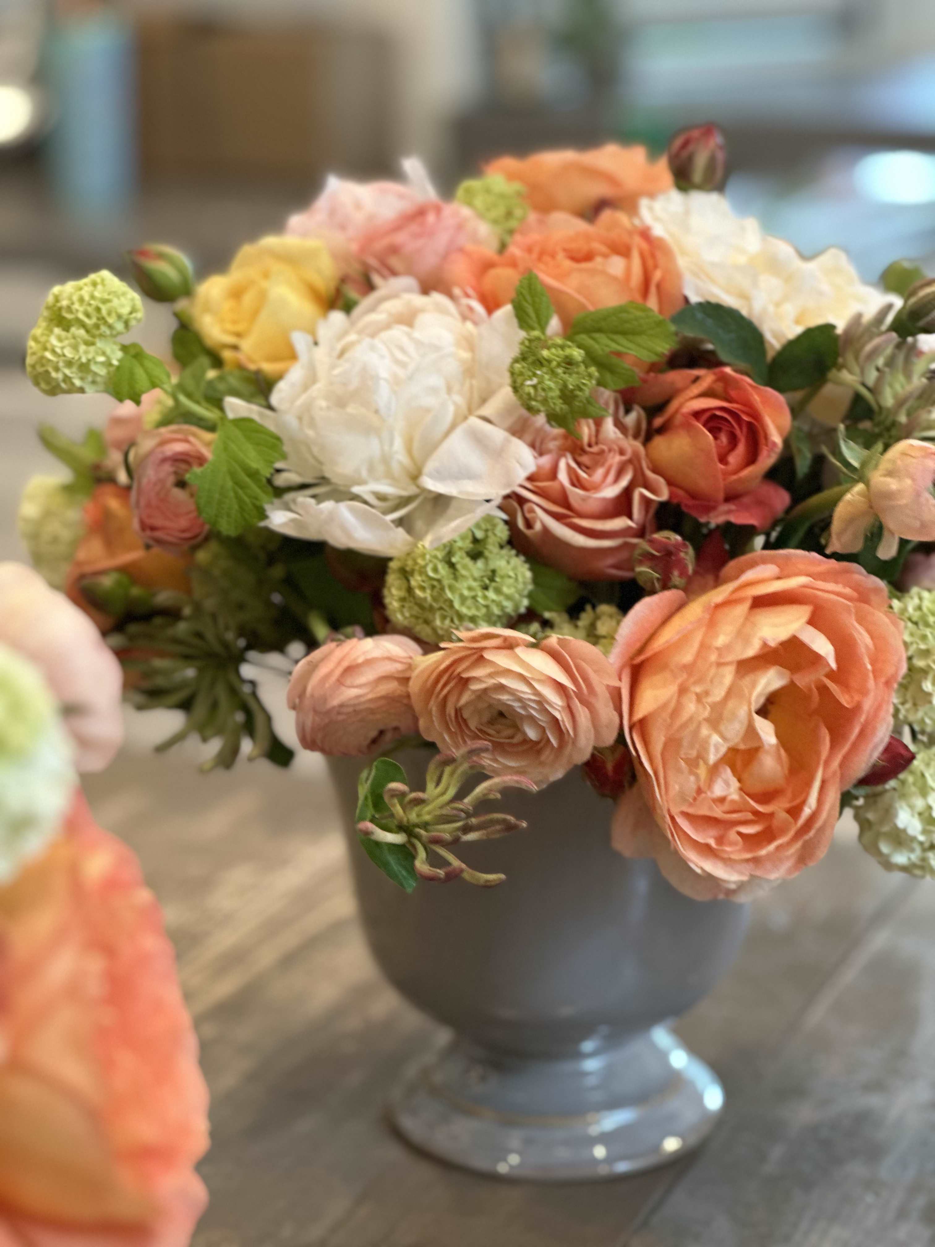 Mixed bouquet of peach, white, and yellow flowers in a gray vase