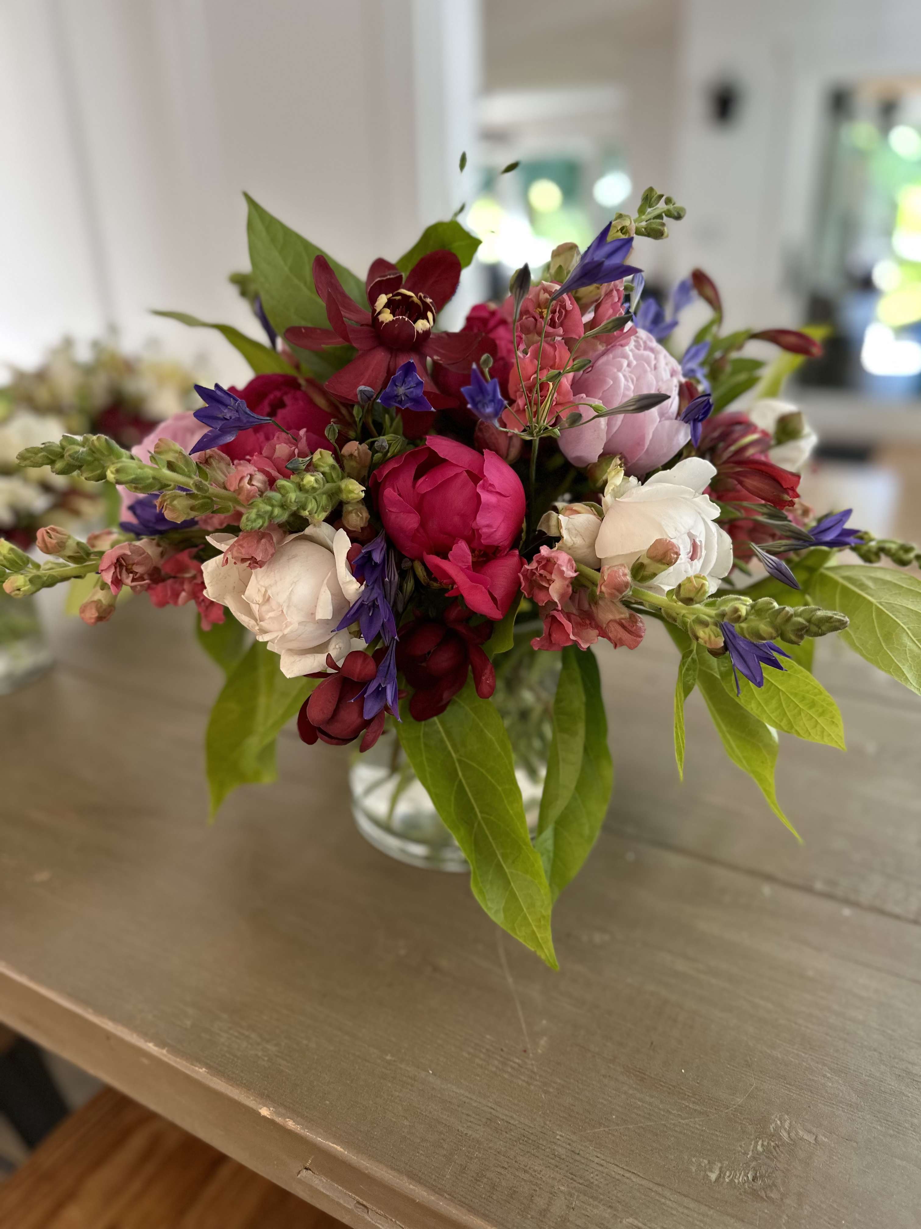 Mixed bouquet of pink, white, and purple flowers in a clear glass vase