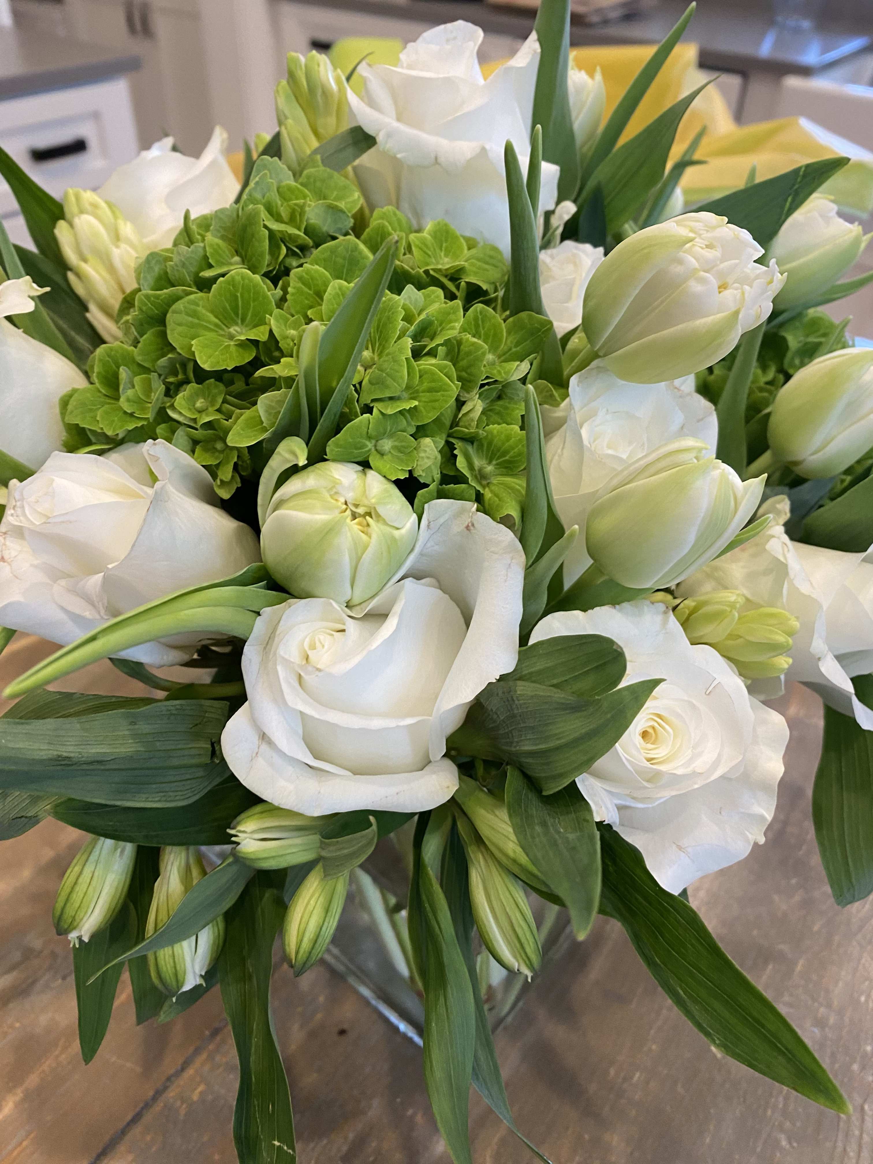 White roses and tulips arranged with a green hydrangea cluster