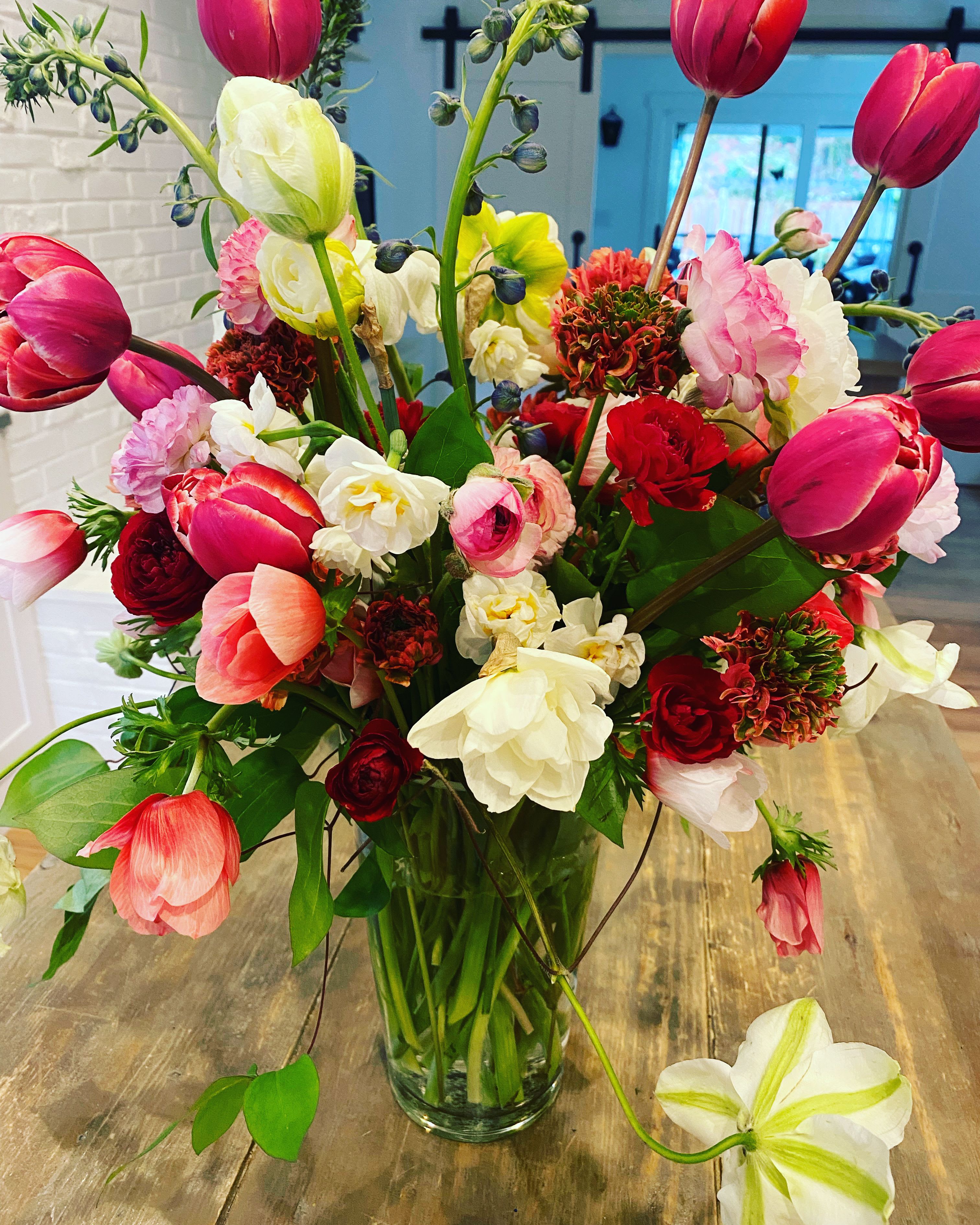 Mixed bouquet of pink, red, and white tulips in a clear glass vase