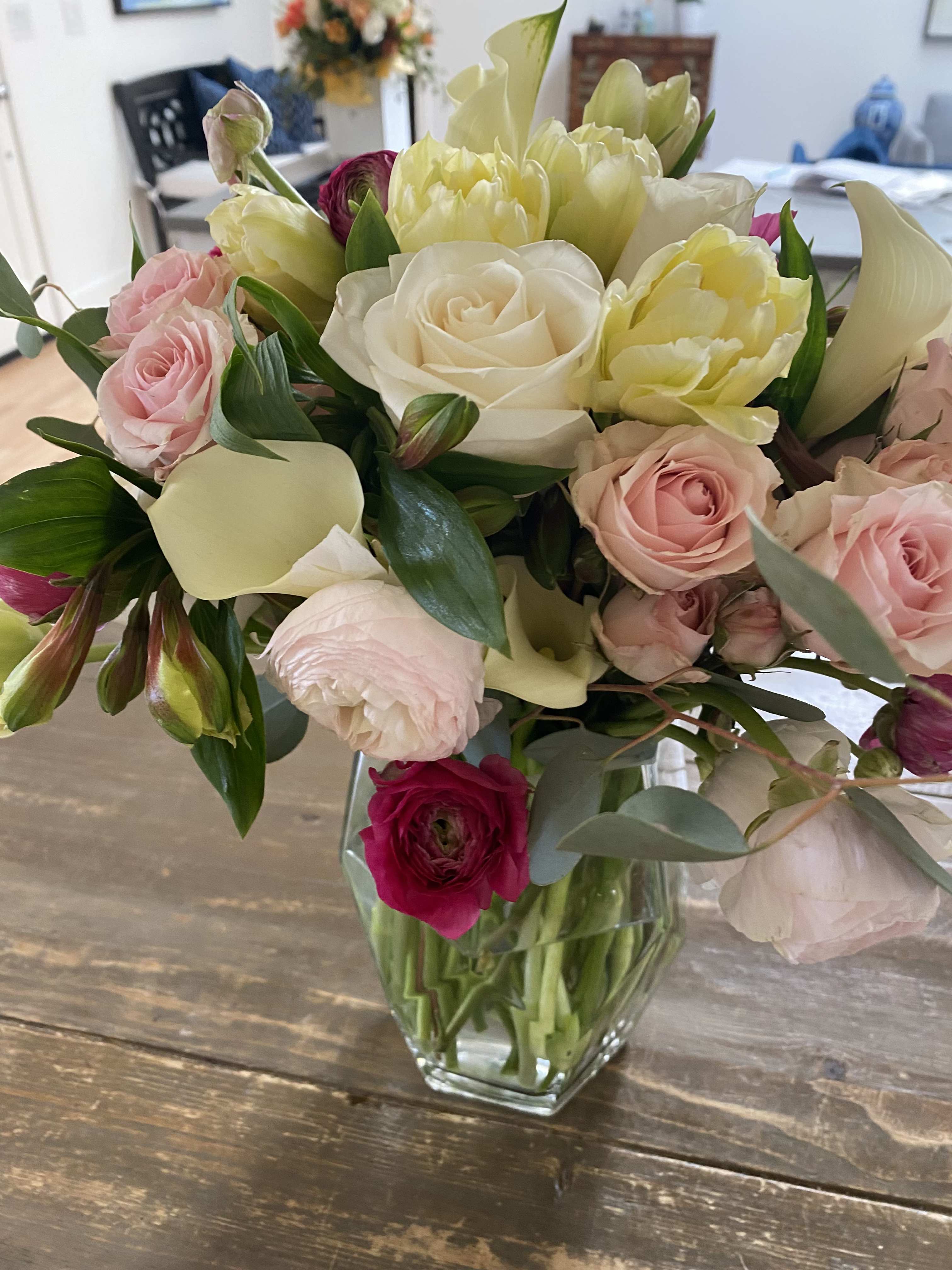 Mixed bouquet of pink, white, and yellow flowers in a clear glass vase