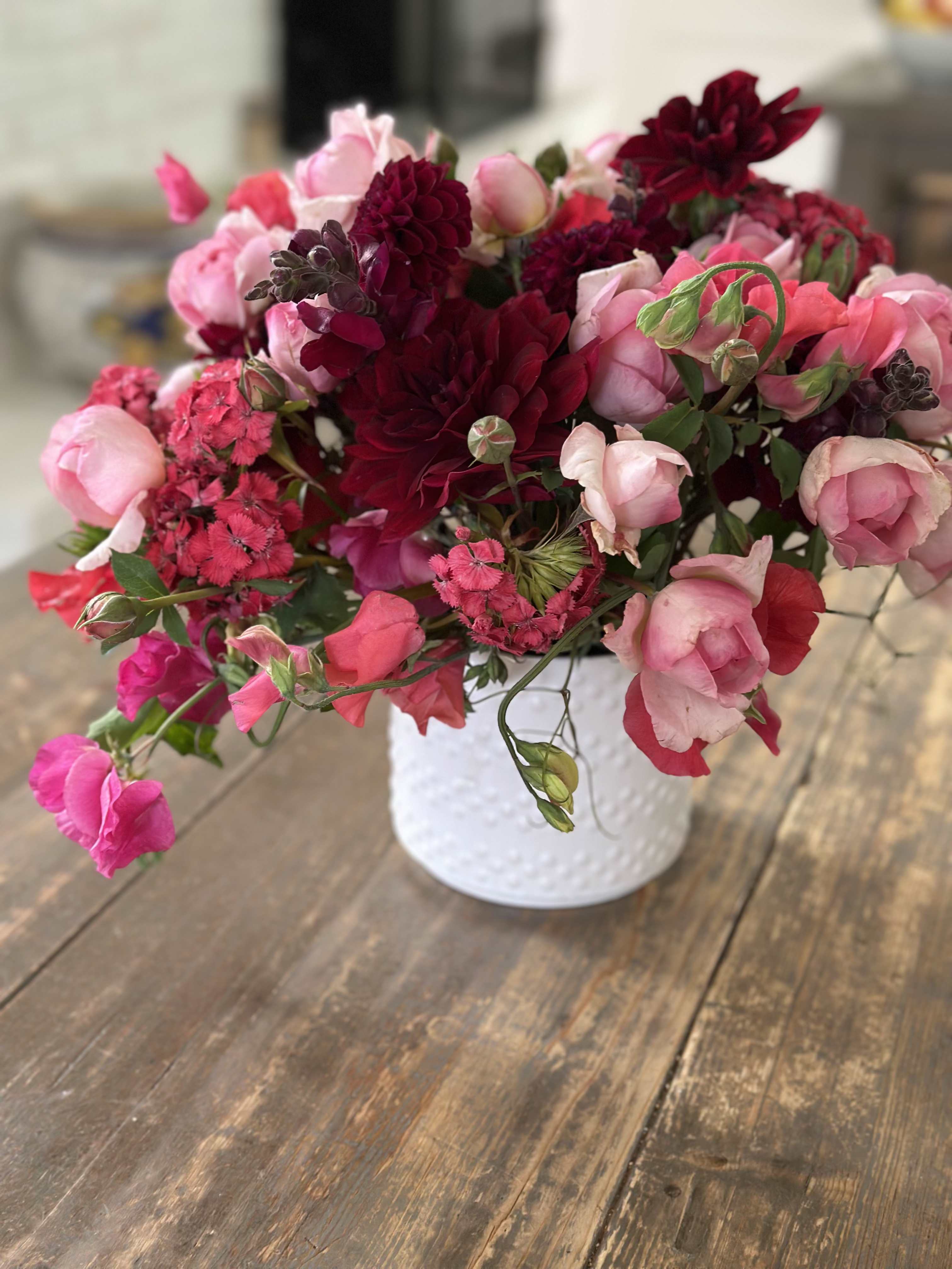 Pink and burgundy flowers arranged in a white vase