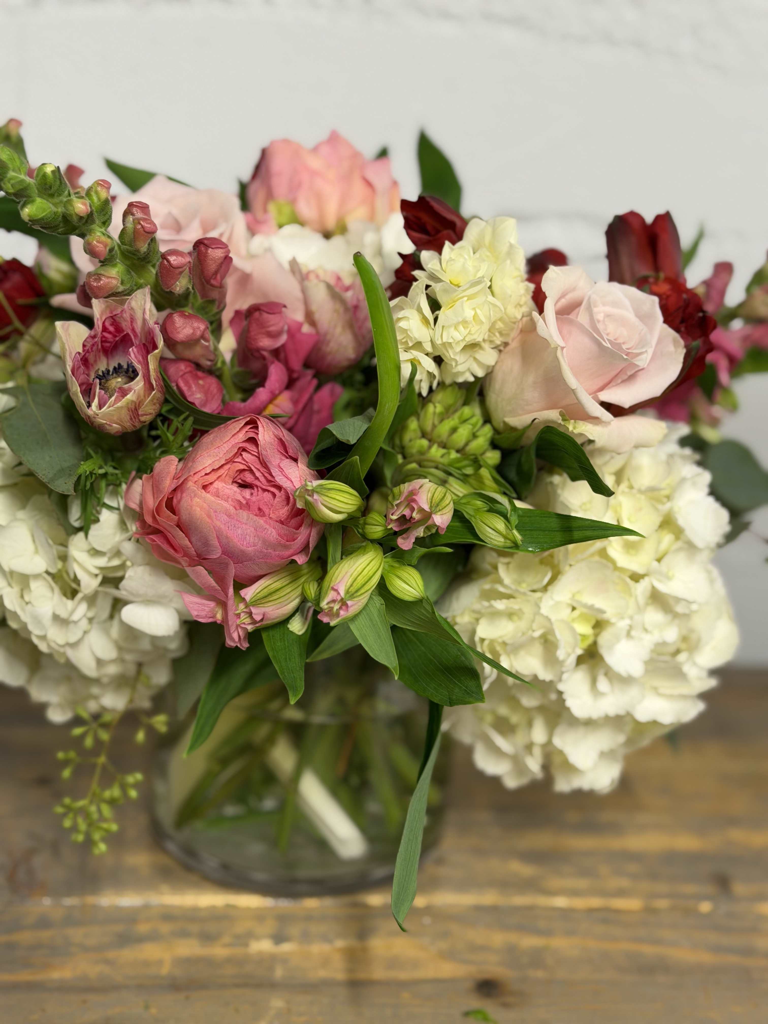 Mixed bouquet of pink, white, and burgundy flowers in a glass vase