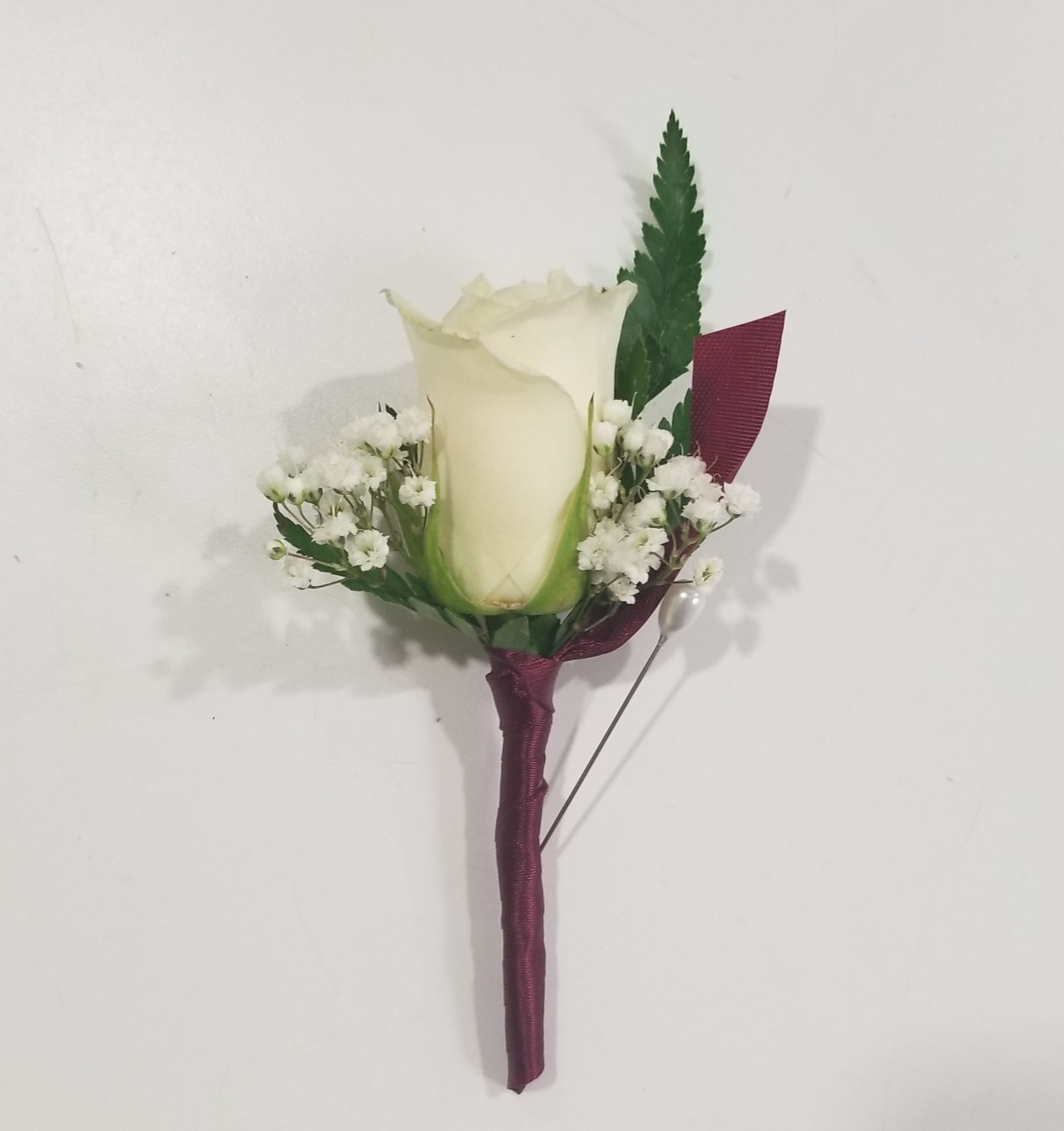 White rose boutonniere with baby's breath and burgundy ribbon