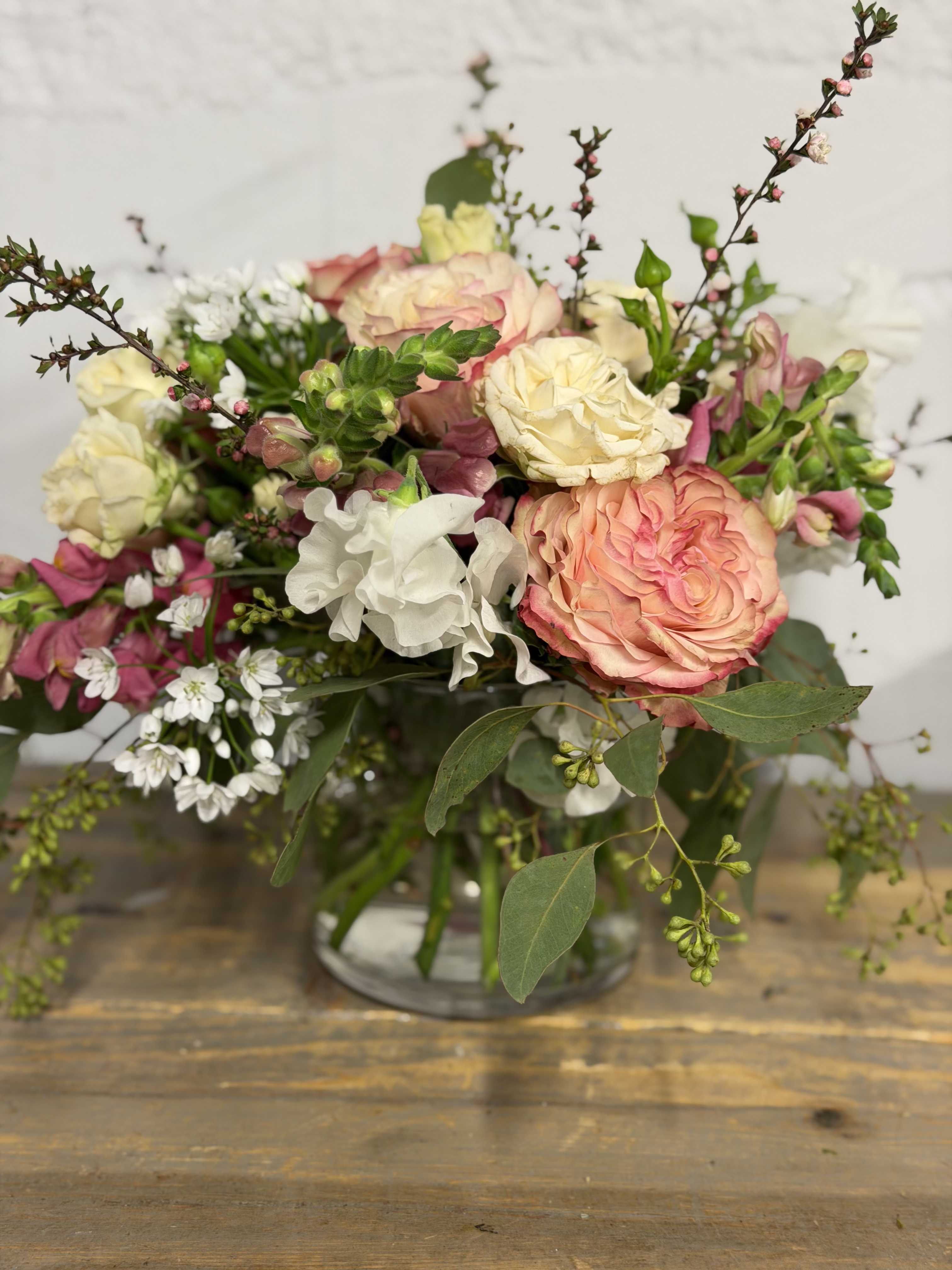 Mixed bouquet of pink, cream, and white flowers in a glass vase