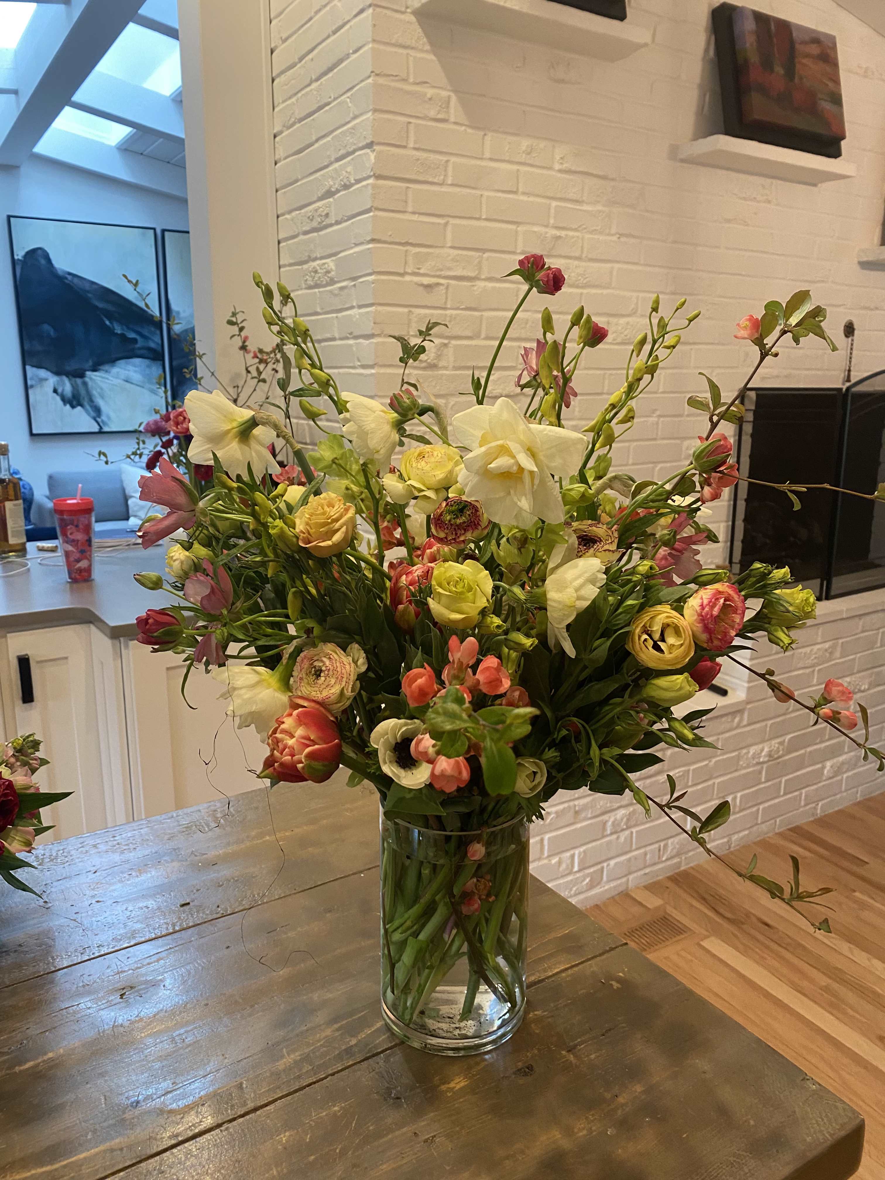 Mixed bouquet of white, pink, and yellow flowers in a clear glass vase