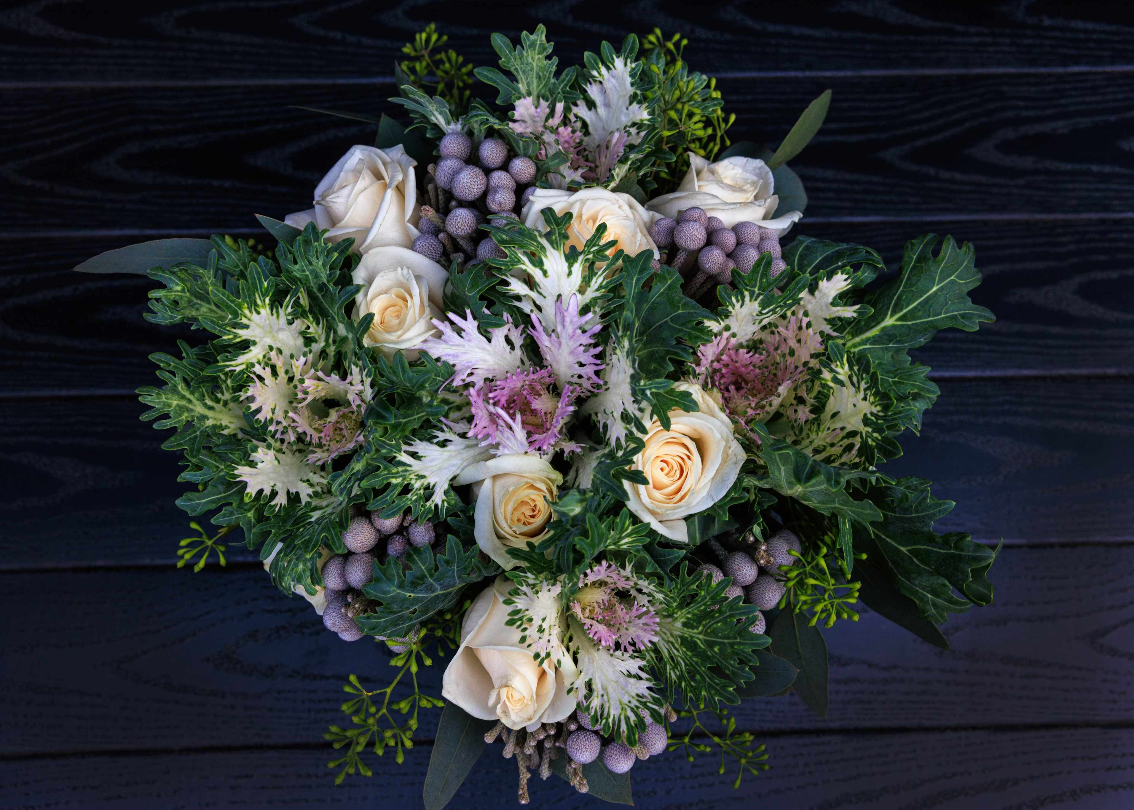 Bouquet of cream roses with purple accents and green foliage