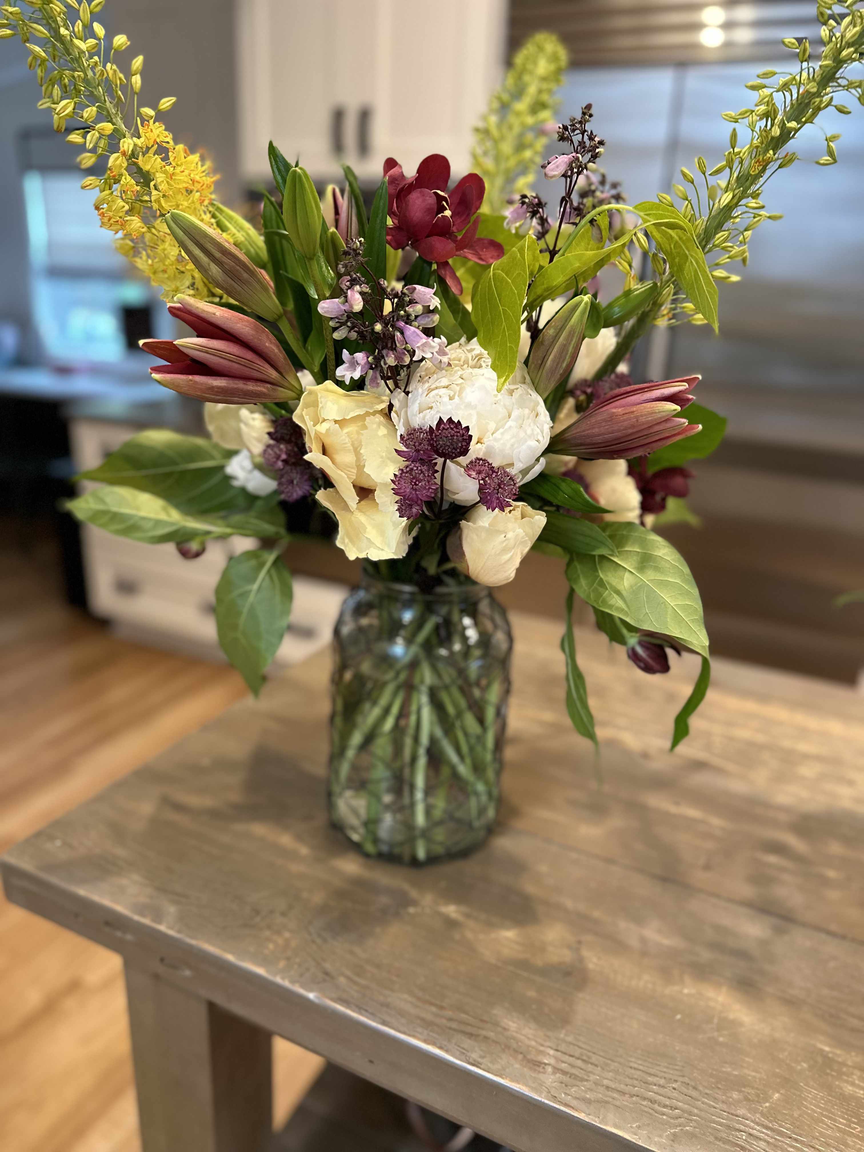 Mixed bouquet in a glass vase with lilies, orchids, and pale blooms