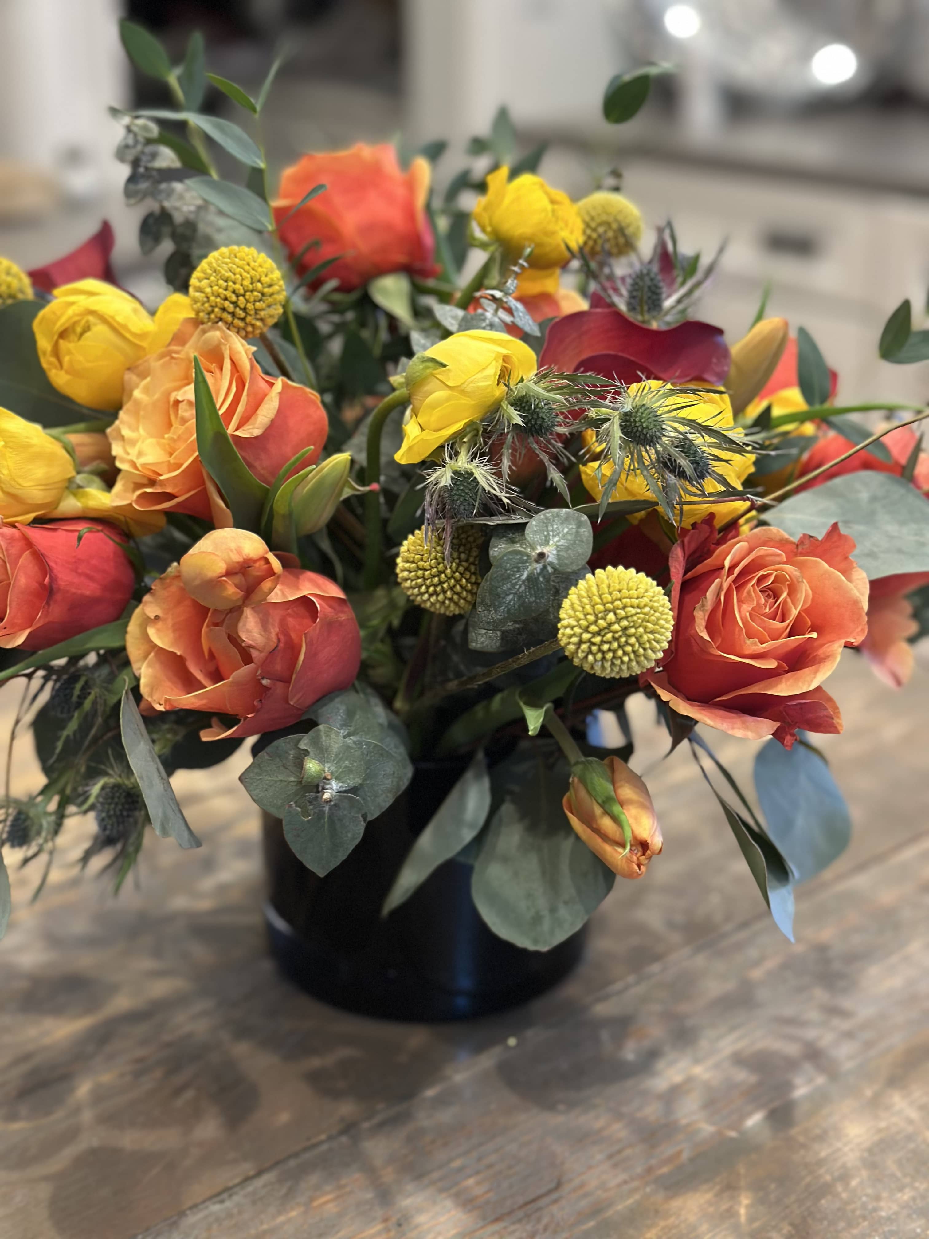 Orange and yellow rose bouquet in a black vase
