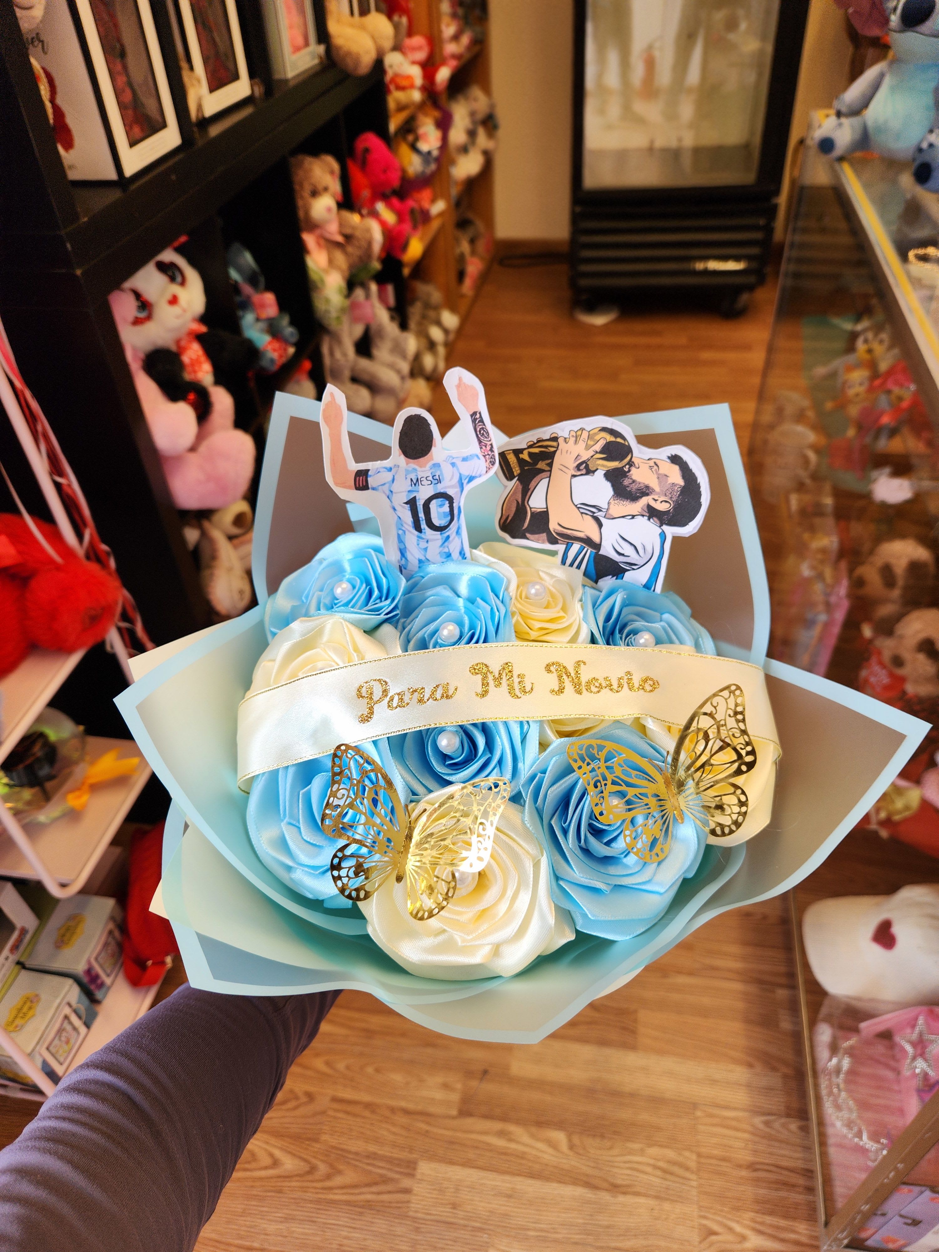 Blue and white rose bouquet with soccer player toppers and butterfly accents