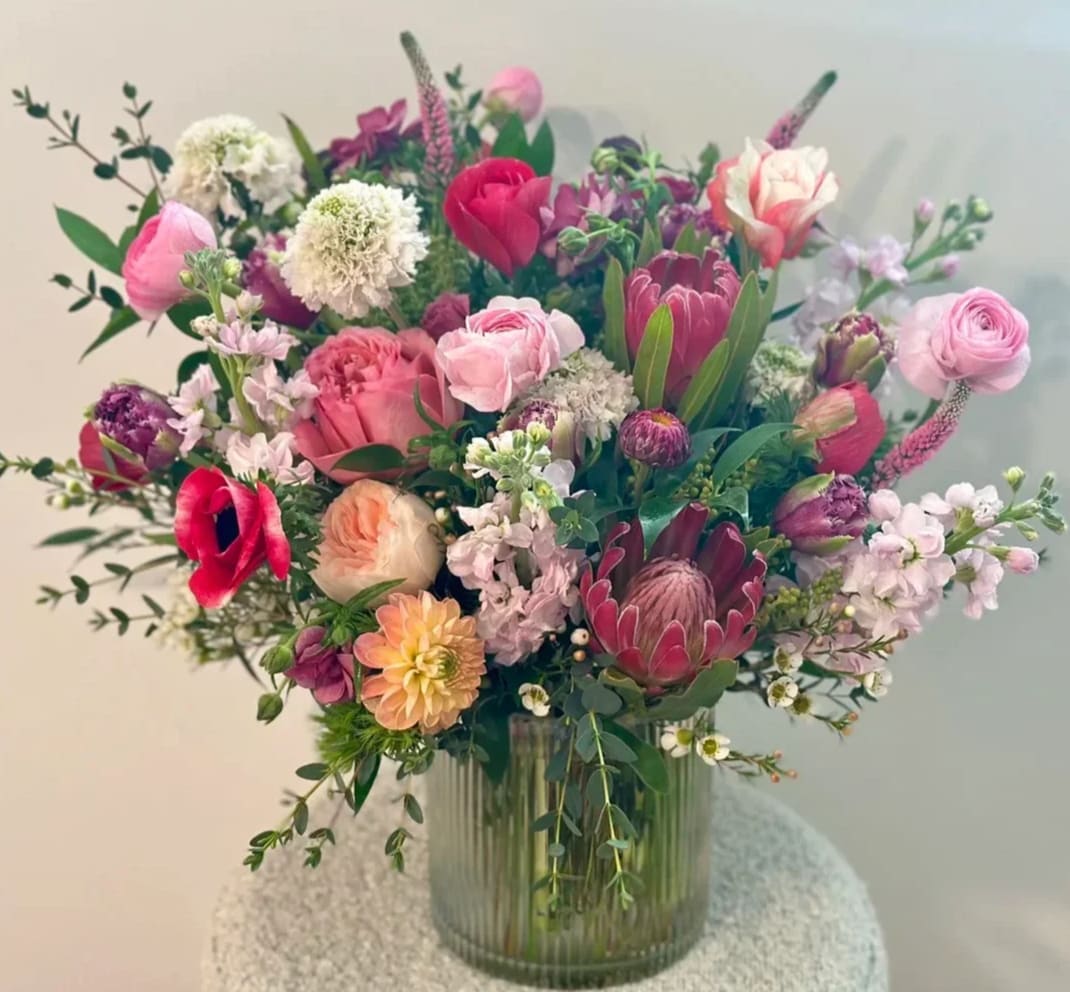 Mixed pink and white floral arrangement in a ribbed glass vase