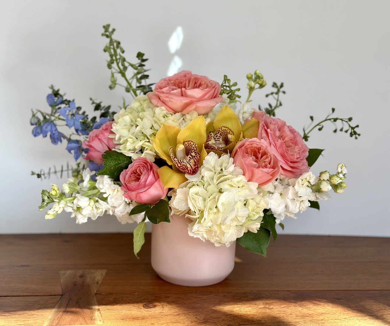Pink roses and white hydrangeas in a blush vase with yellow orchids