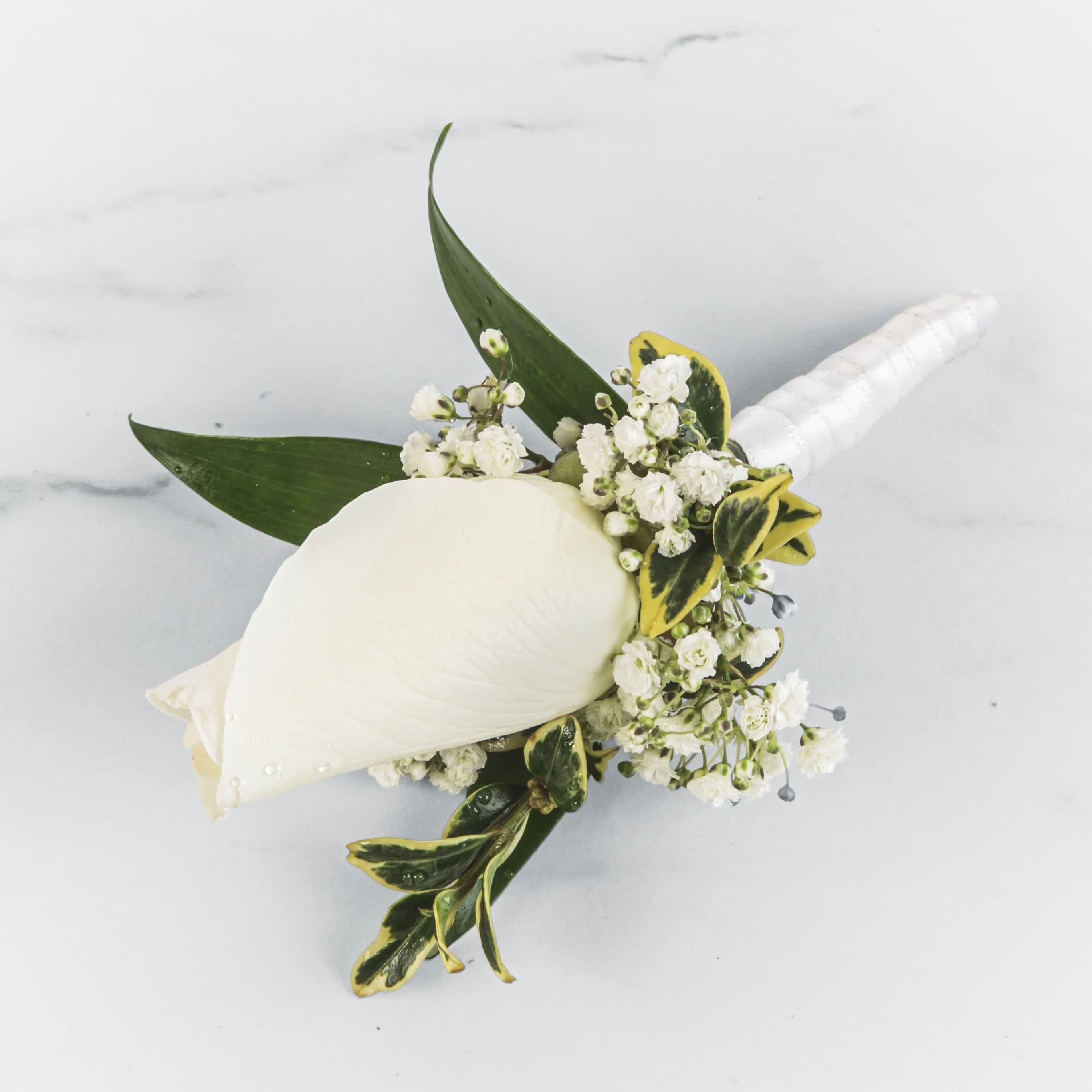 White calla lily boutonniere with small white blossoms and green leaves