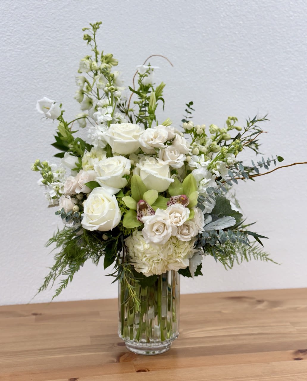 White floral arrangement in a clear glass vase with mixed blooms and greenery