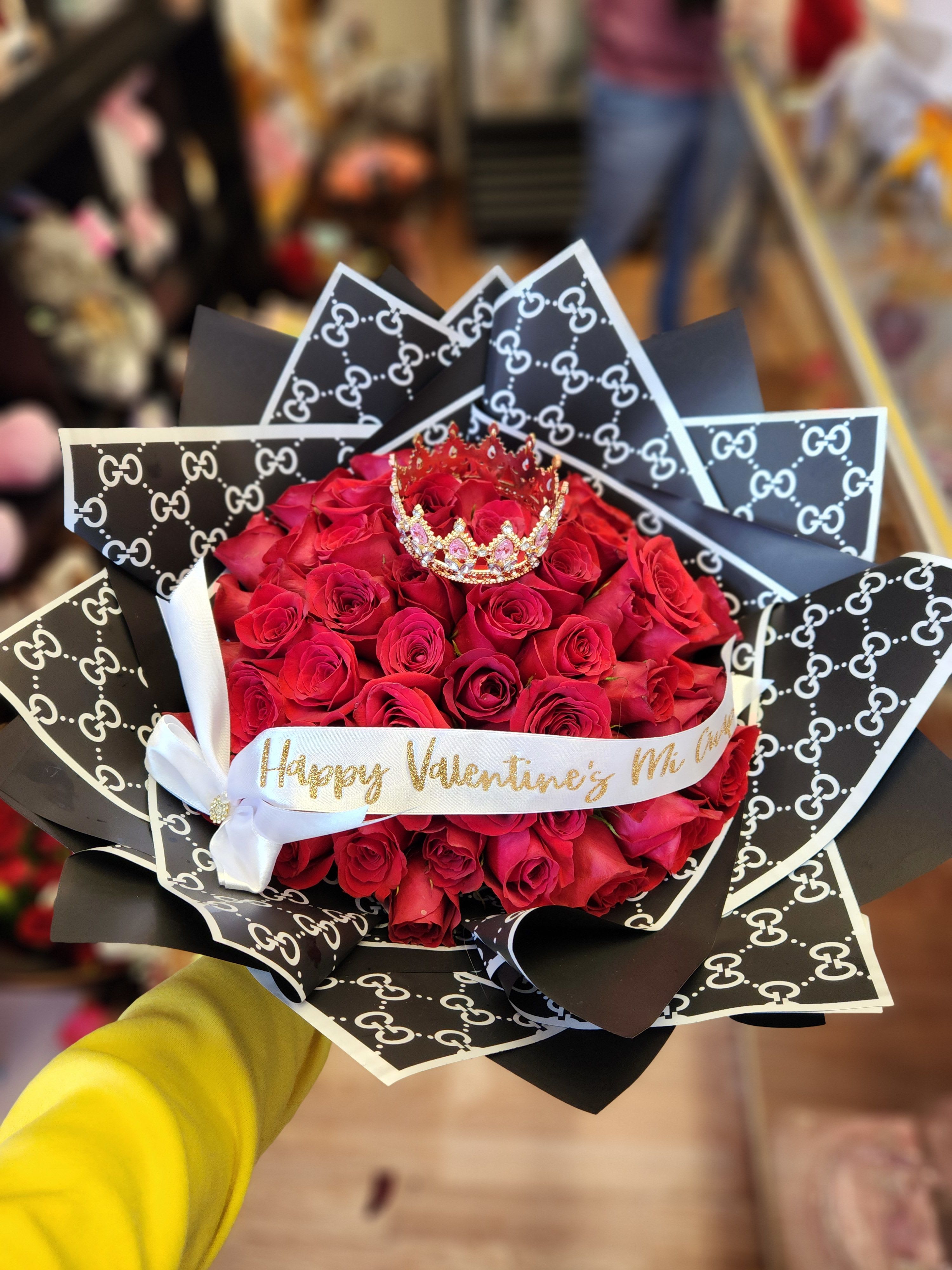Bouquet of red roses with a small crown and patterned black wrapping