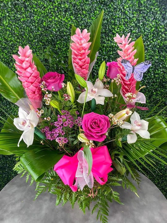 Pink tropical floral arrangement with roses, orchids, and lilies