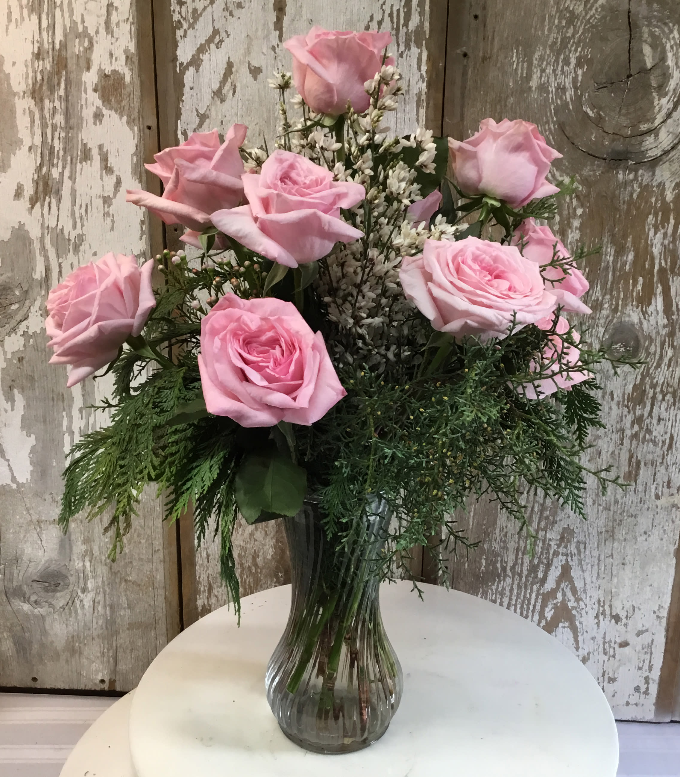 Pink roses arranged in a clear glass vase with white filler flowers