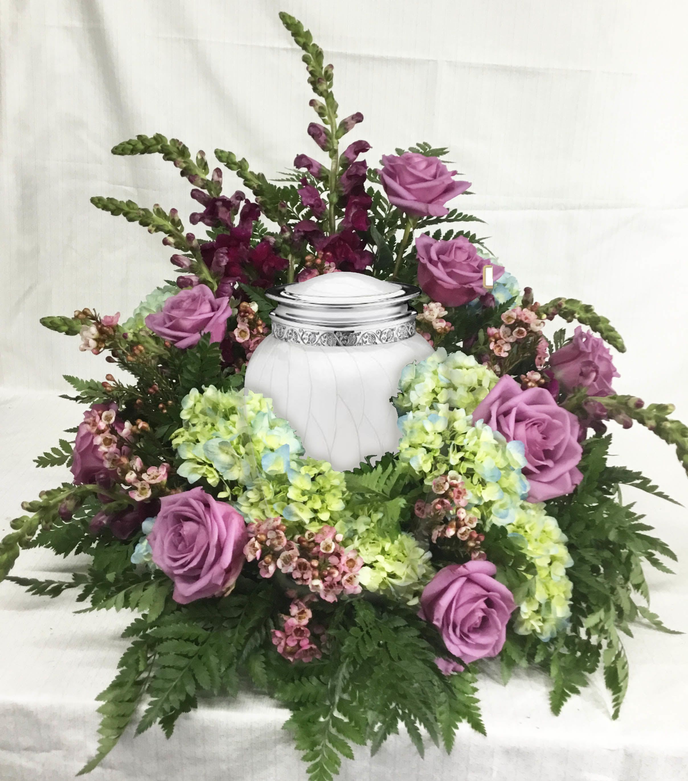 Lavender roses and hydrangeas arranged around a white urn