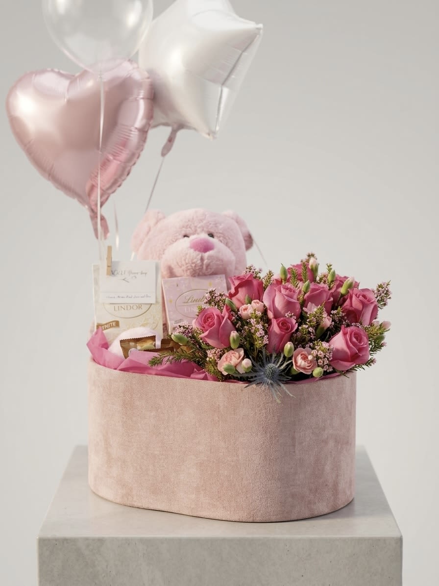 Blush Love Gift Box - A charming all-in-one gift designed to melt hearts. This elegant blush velvet box features a lush arrangement of fresh pink roses accented with delicate filler flowers, paired with a soft plush teddy bear, premium chocolates, and festive heart-shaped balloons. Perfect for birthdays, anniversaries, or romantic surprises, this gift set delivers sweetness, beauty, and joy in one unforgettable presentation.