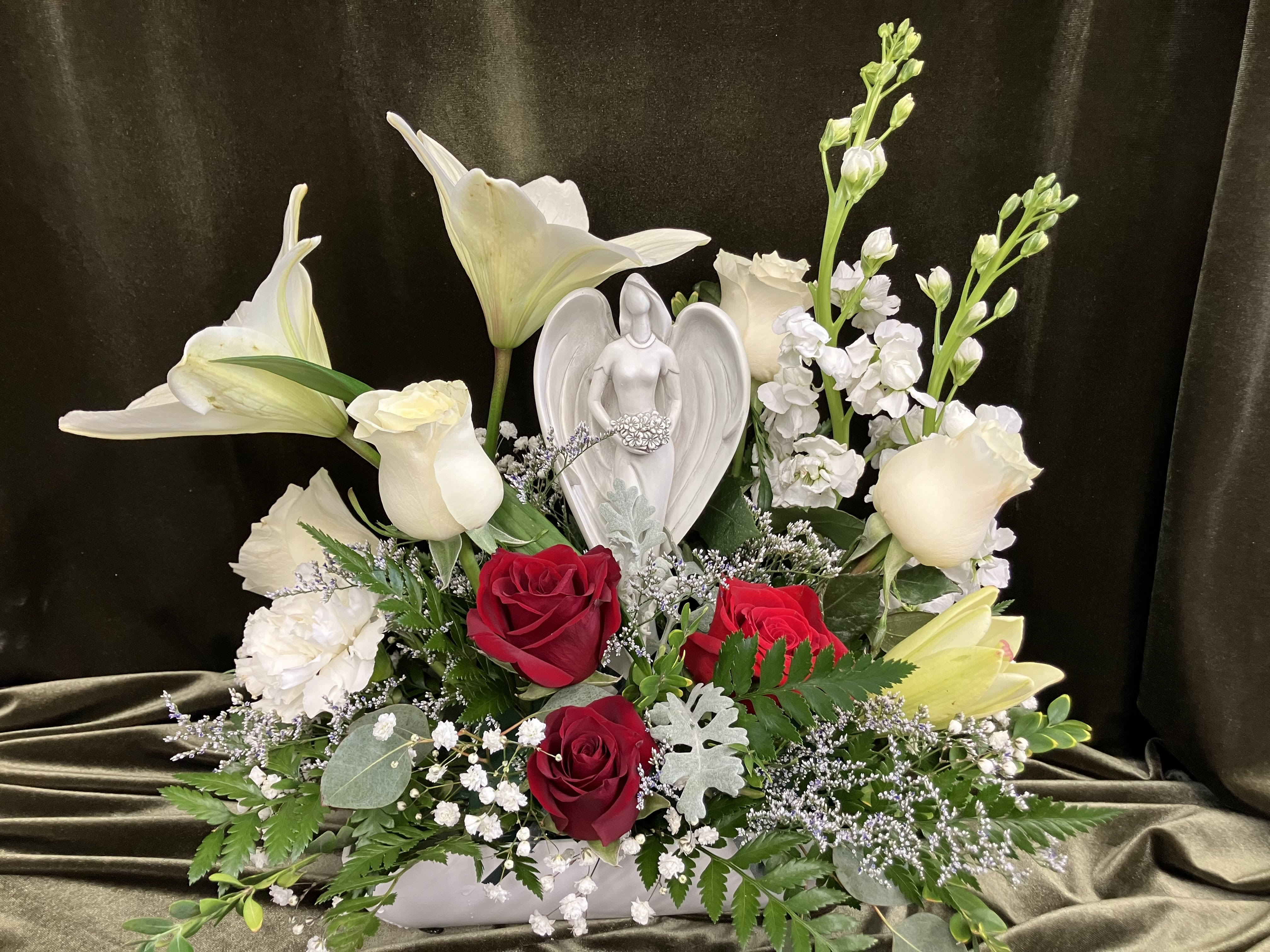 Angel in Flower garden - Here we have a thoughtful flower gift with a keepsake angel, the perfect way to show your sympathy when someone special passes away, a sweet angel statue holding a bouquet of flowers surrounded by fresh flowers. 