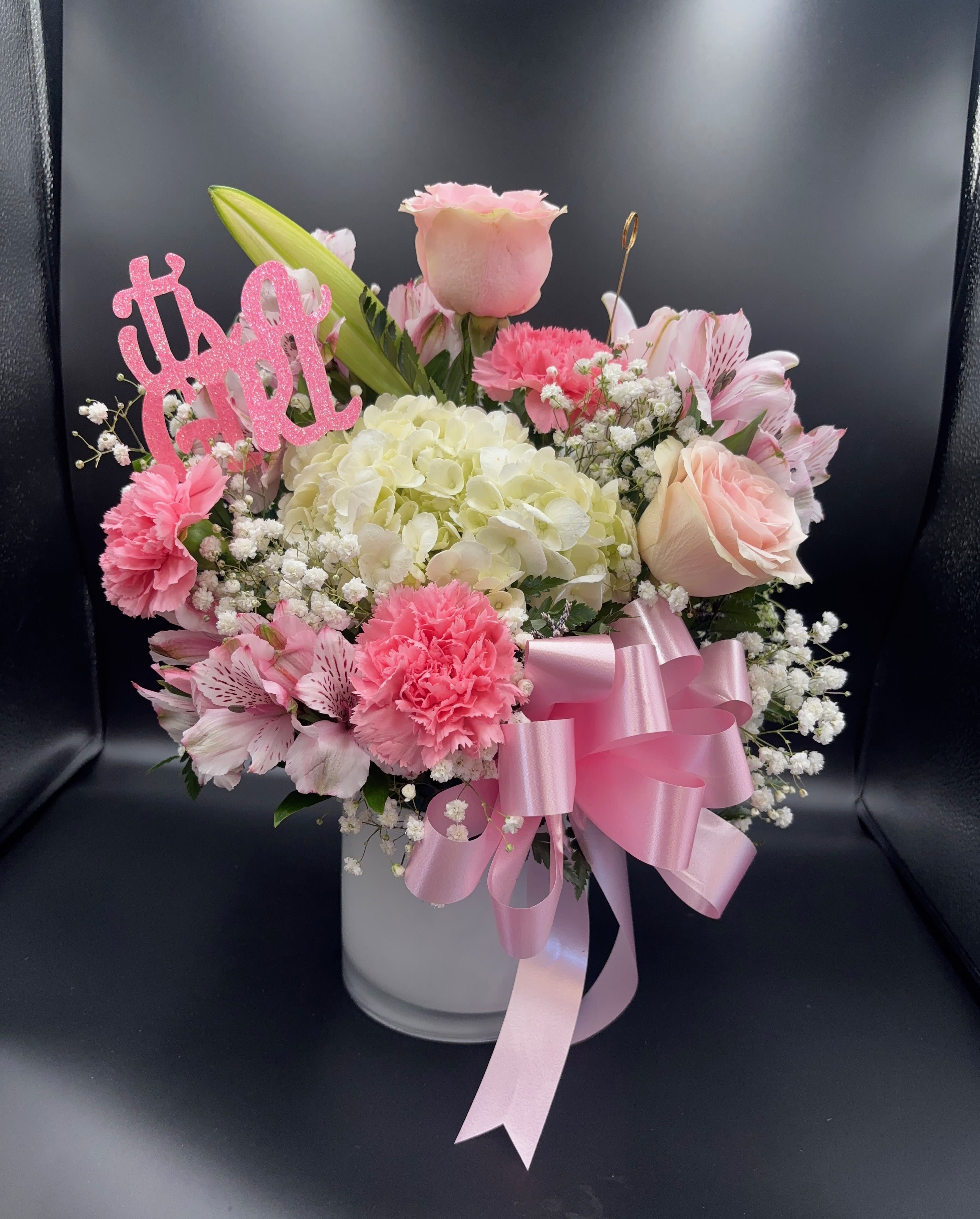 Pink and white flower arrangement in a white vase with a ribbon bow