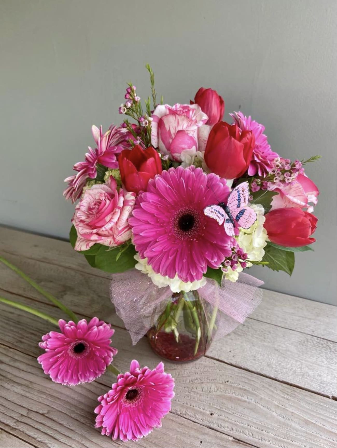 Pink and red mixed bouquet in a glass vase with a ribbon bow
