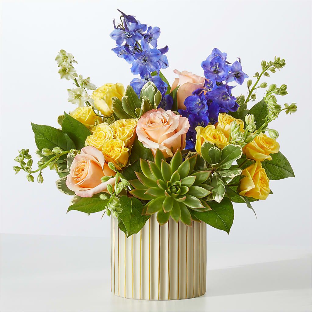 Cobalt Reverie Bouquet - Get swept away by this daydream of a bouquet, arranged with peachy roses, white mini carnations and striking blue delphinium.  2 Dark Blue Delphinium stems 2 White Larkspur stems 3 Peach 50 cm Roses 2 Yellow Spray Rose stems 2 White Mini Carnation stems 1 Succulent 2 Salal tips 1 Variegated Pittosporum stem