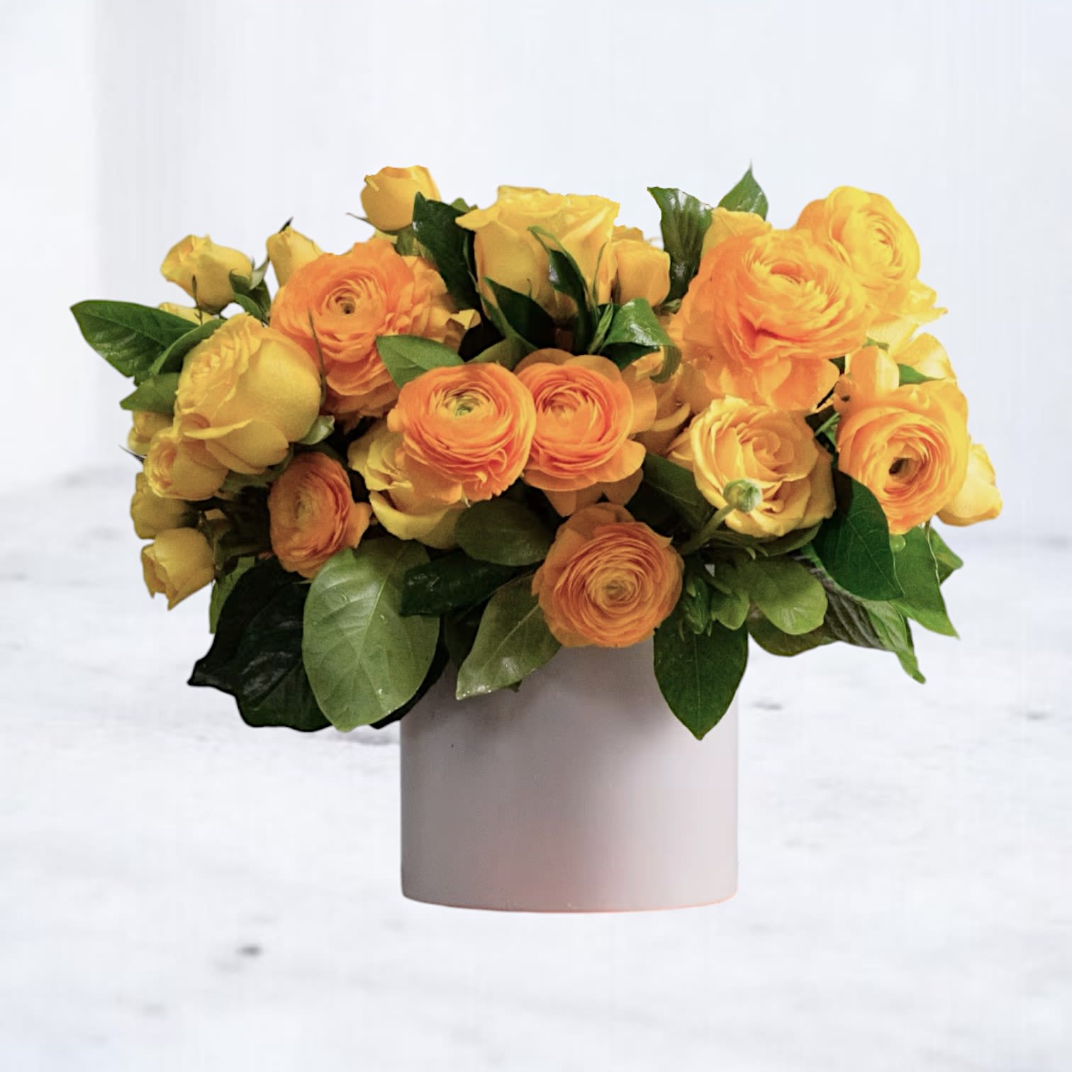 Citrus Coil - Spiraling with golden cheer, Citrus Coil is a radiant medley of golden yellow roses, vibrant orange ranunculus, and fresh green foliage, all tucked into a clean, modern vase. This monochromatic design makes a striking gift for celebrating milestones, saying “thank you,” or simply sending a dose of happiness.  Lush, sculptural, and full of joy, it’s the perfect way to share sunshine—whether for a grand gesture or a meaningful moment.