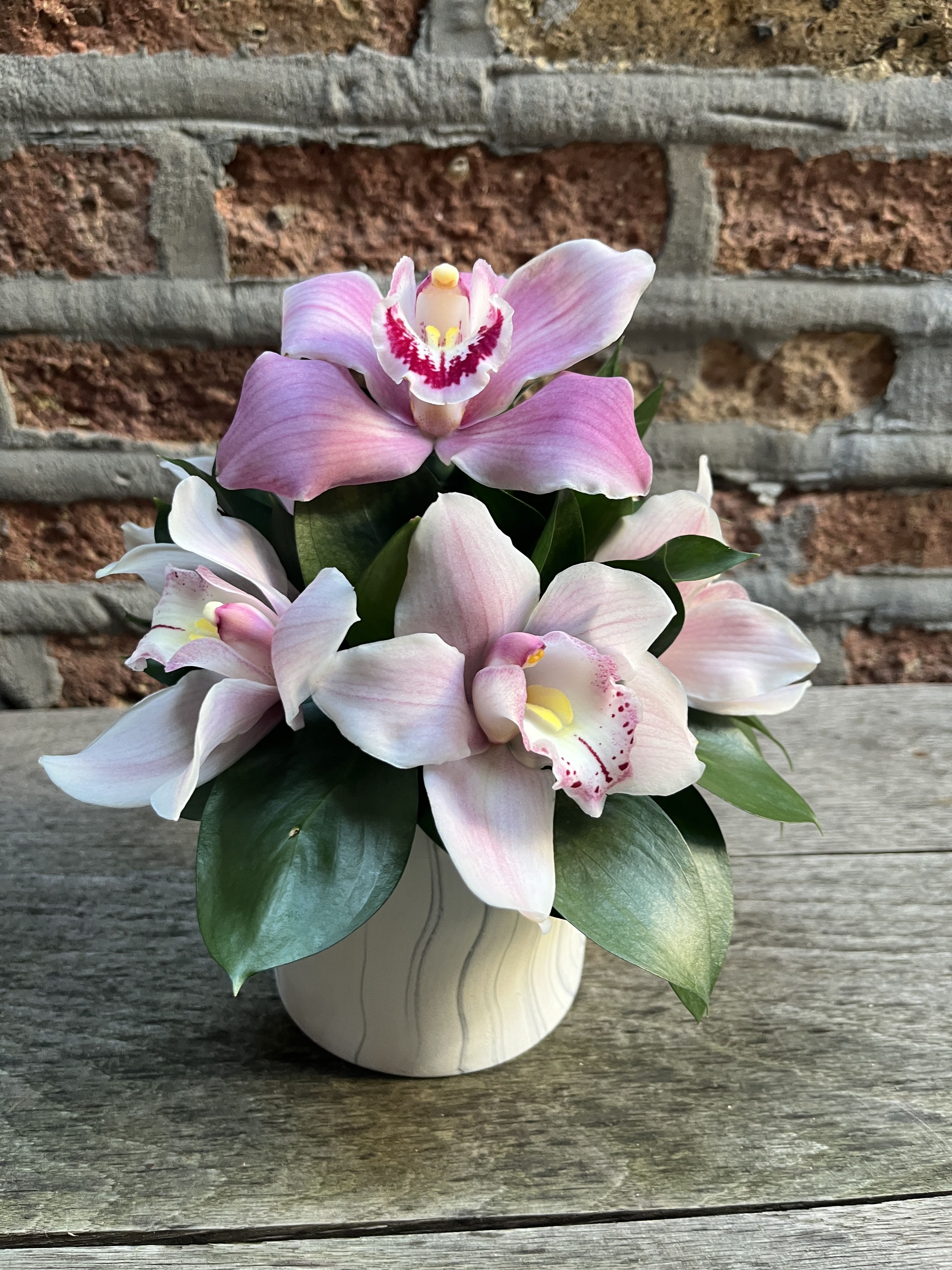 Pink orchids arranged in a small ceramic pot