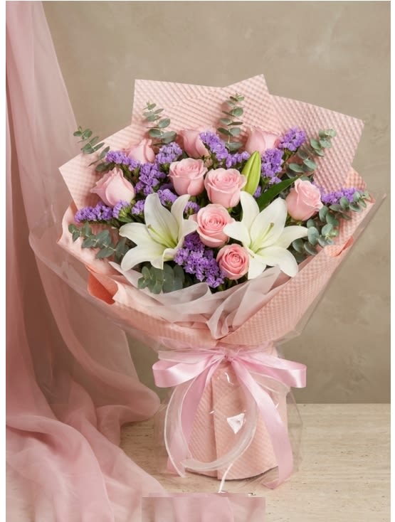 Pink roses and white lilies in a wrapped bouquet with a satin ribbon