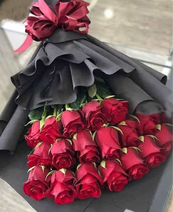 Bouquet of red roses wrapped in black paper with a burgundy bow